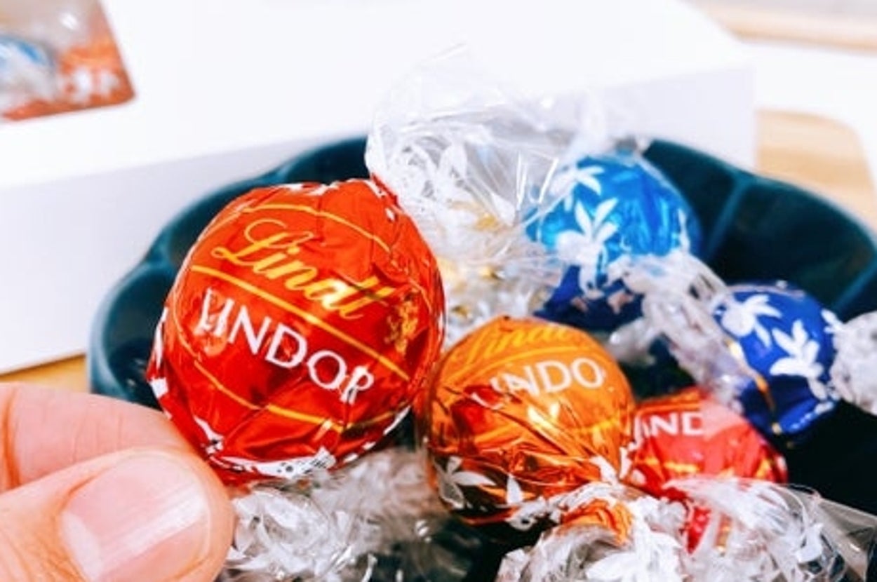 皿に盛られたリンツのチョコボール。手に1つ持っています。背景に箱が見えます。