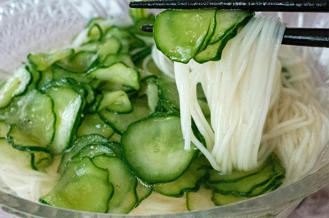ガラスの器に入ったきゅうりたっぷり白だしそうめんを箸で持ち上げている。