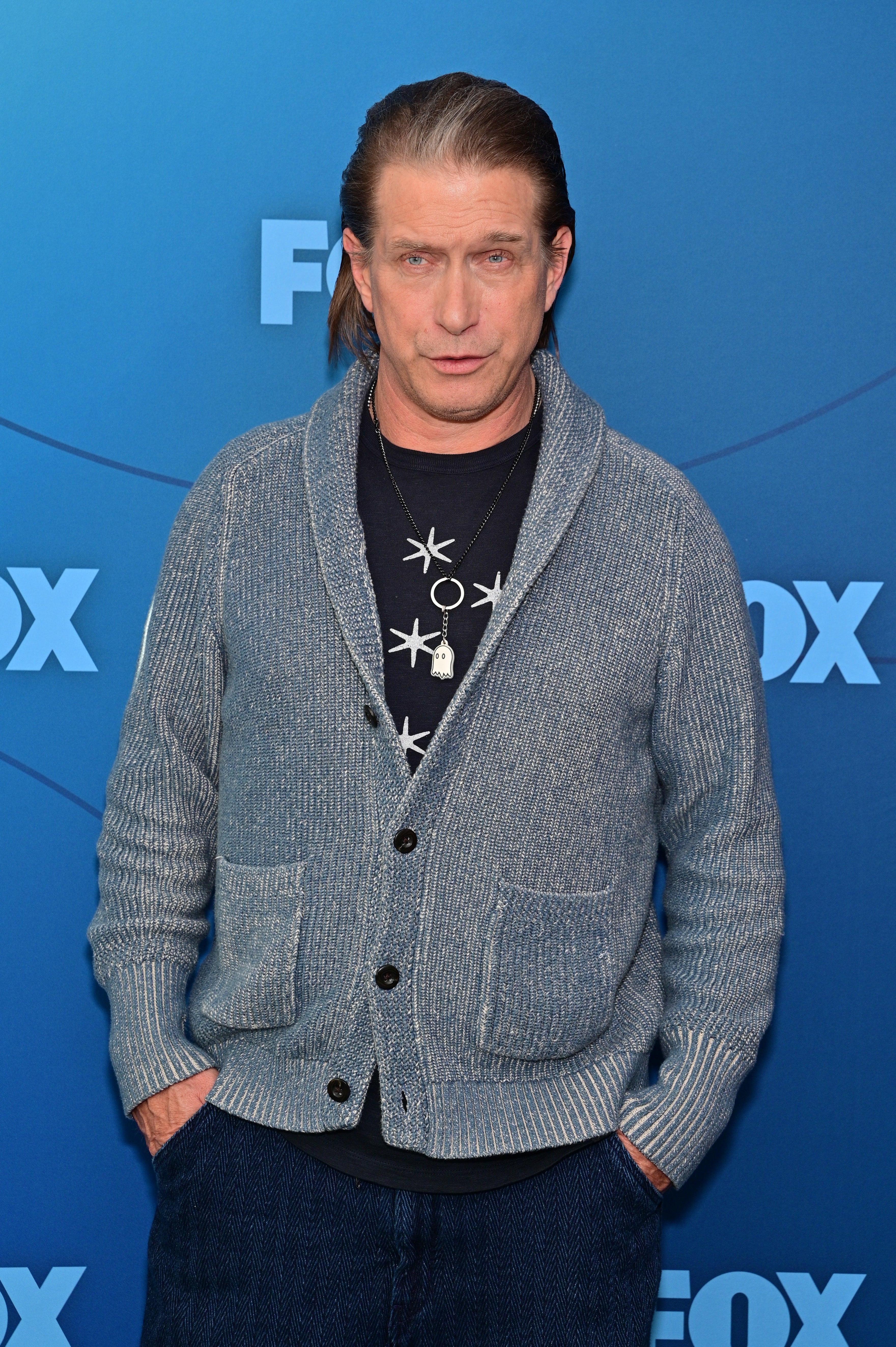 Person successful a casual outfit with a cardigan and patterned garment poses astatine a media event