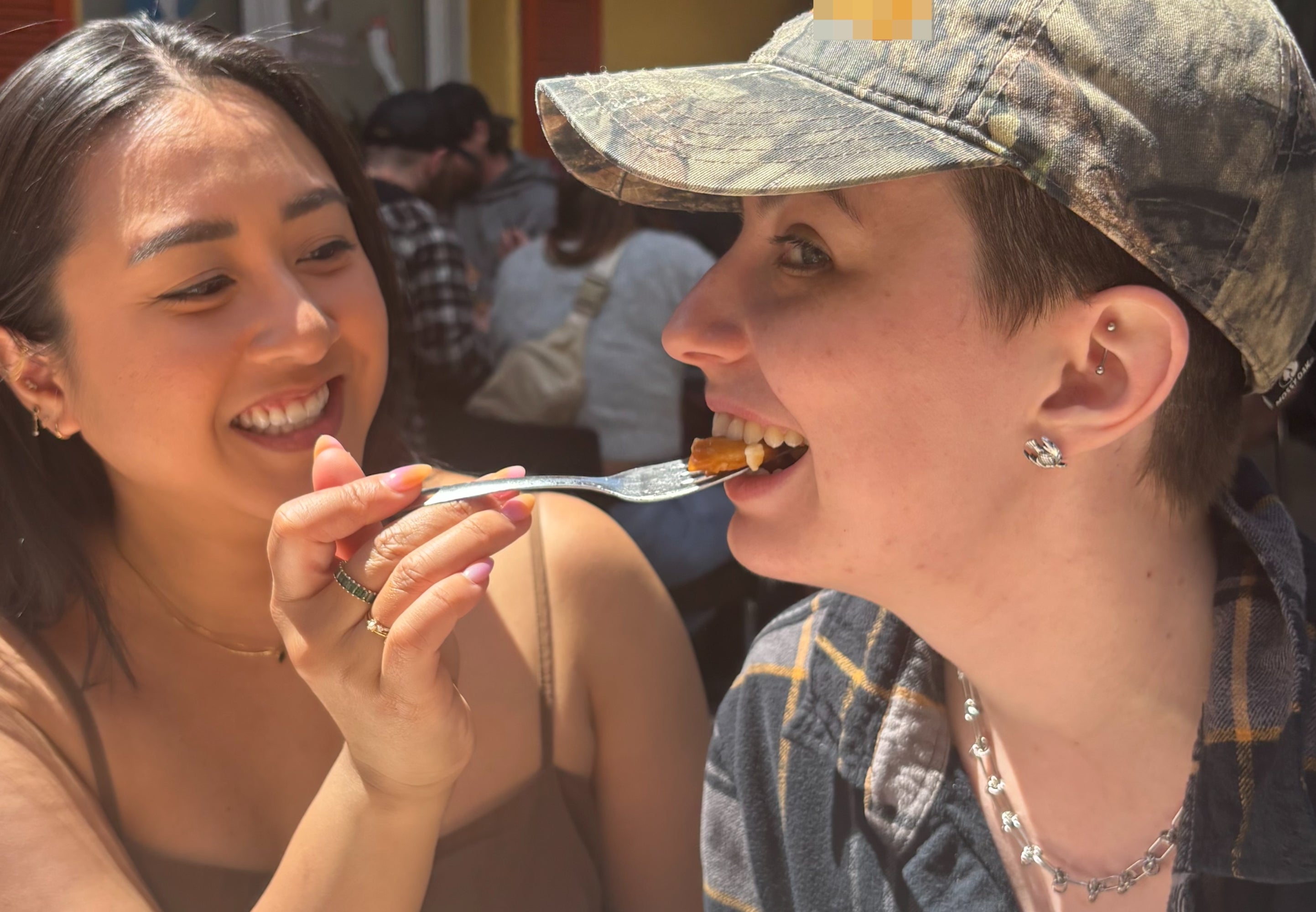 Person smiling feeds different wound from a fork outdoors; some deterioration casual tops and 1 has a camouflage hat