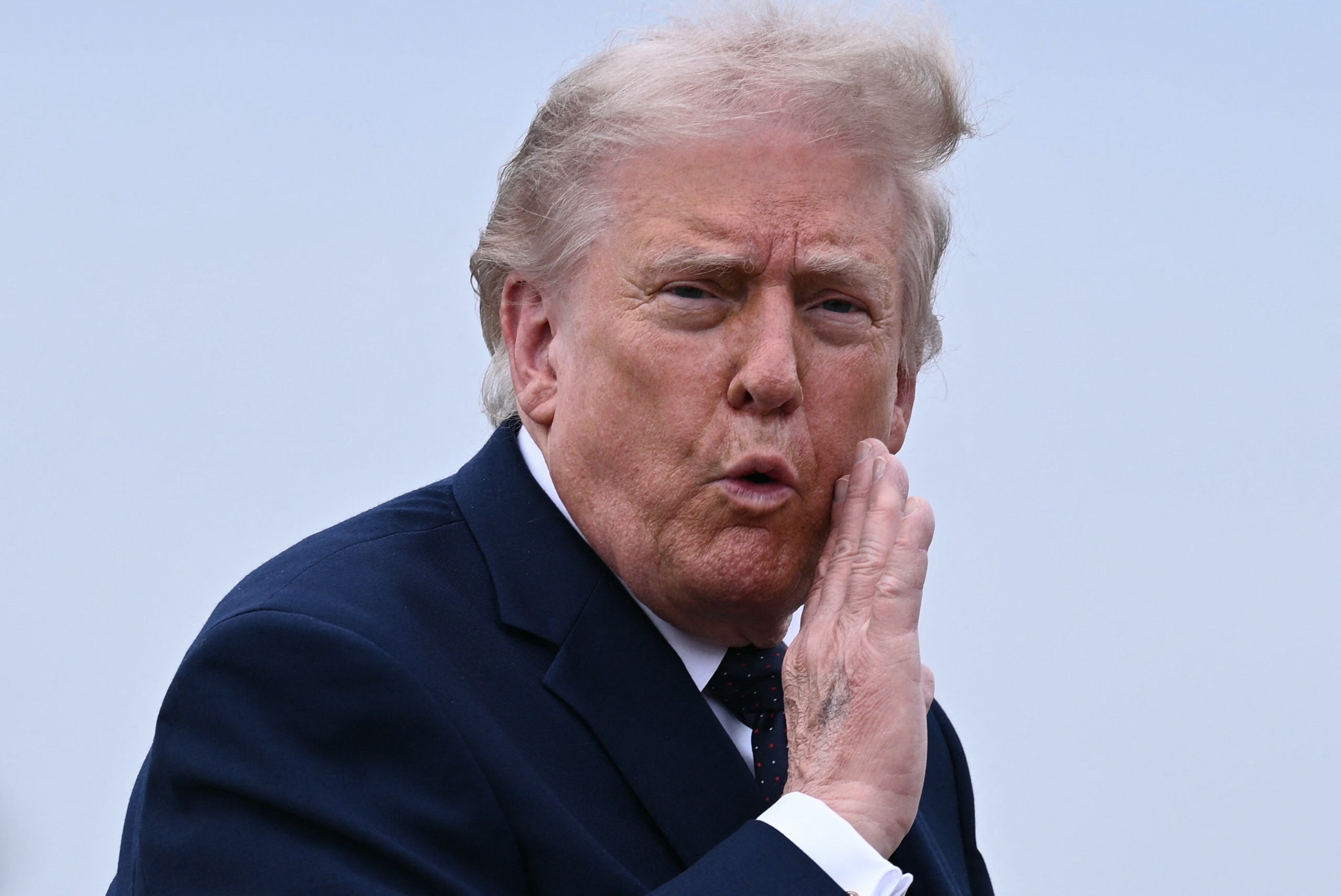 Person successful  a suit   is outdoors, gesturing with a manus  adjacent   their face, appearing to either talk  oregon  shout