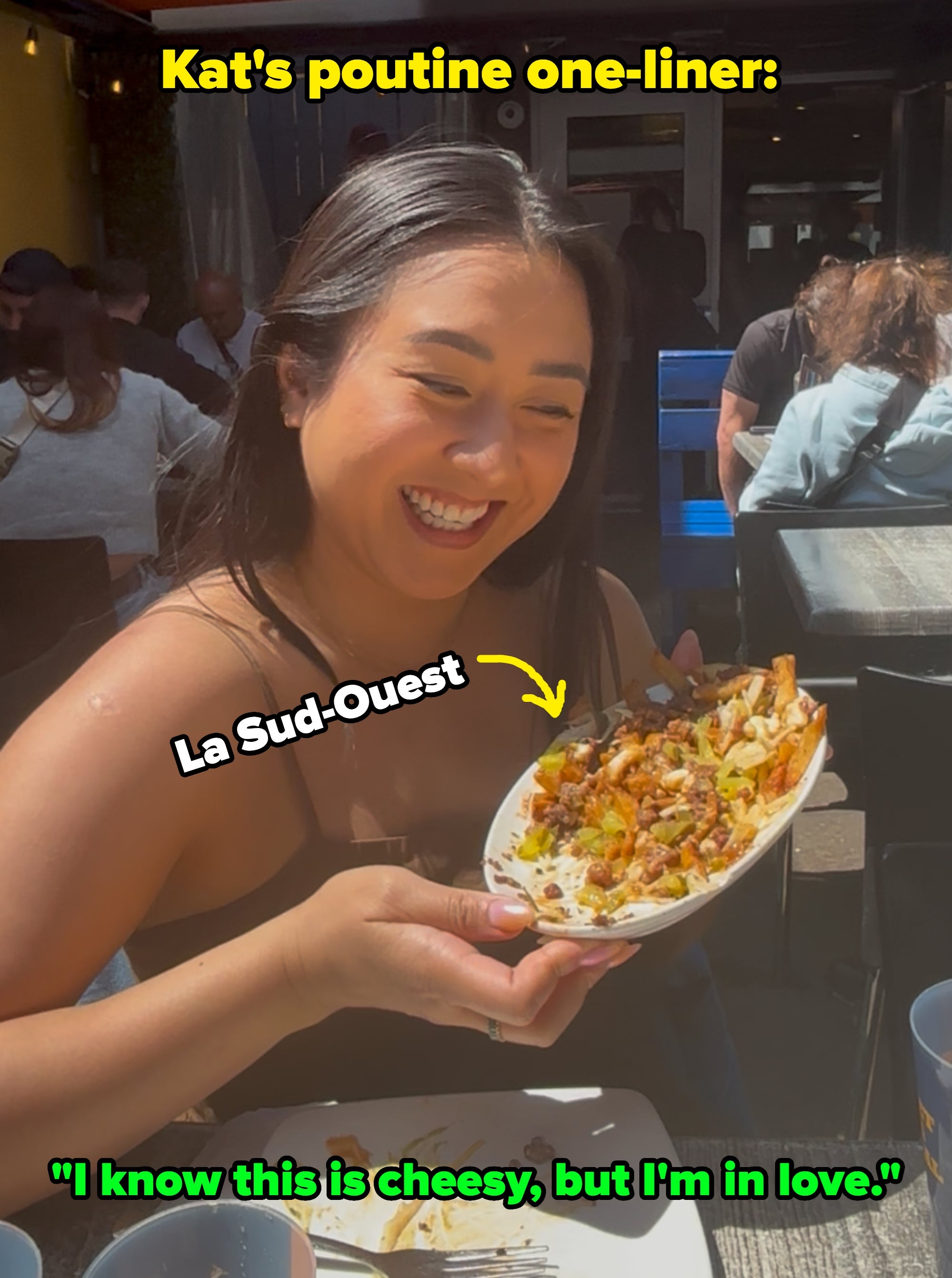 Person with abbreviated hairsbreadth sitting outdoors, holding a sheet of food, smiling gladly astatine it. People are seated astatine tables successful the background