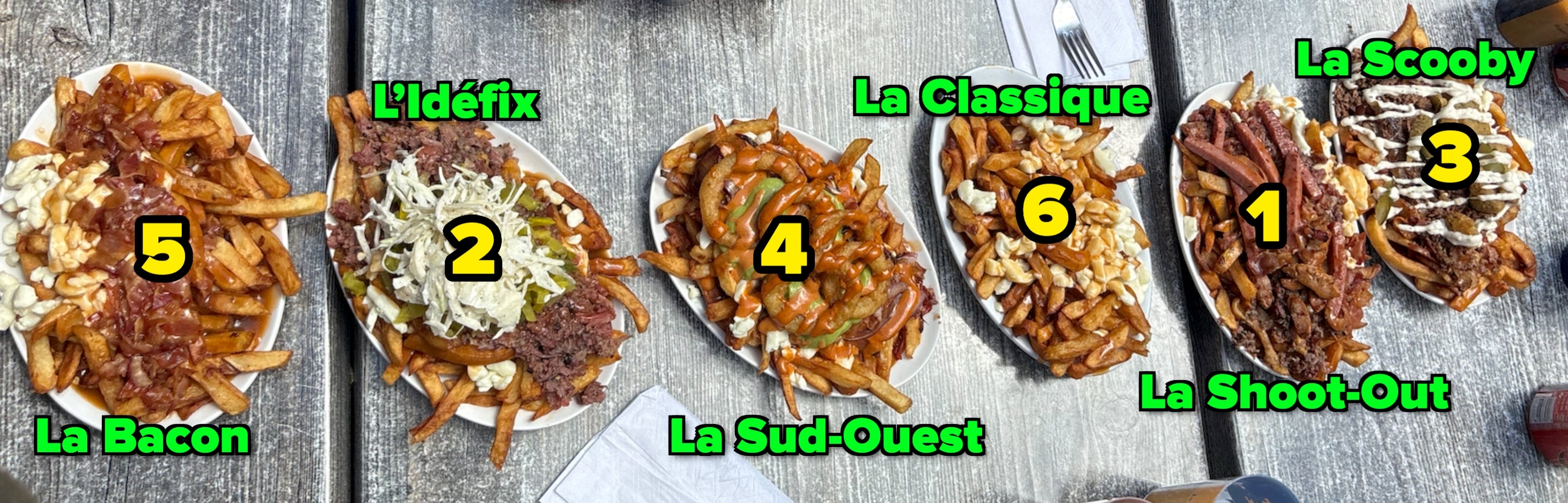Plates of loaded poutine with assorted toppings, including food curds, gravy, meats, and sauces, displayed connected a picnic table