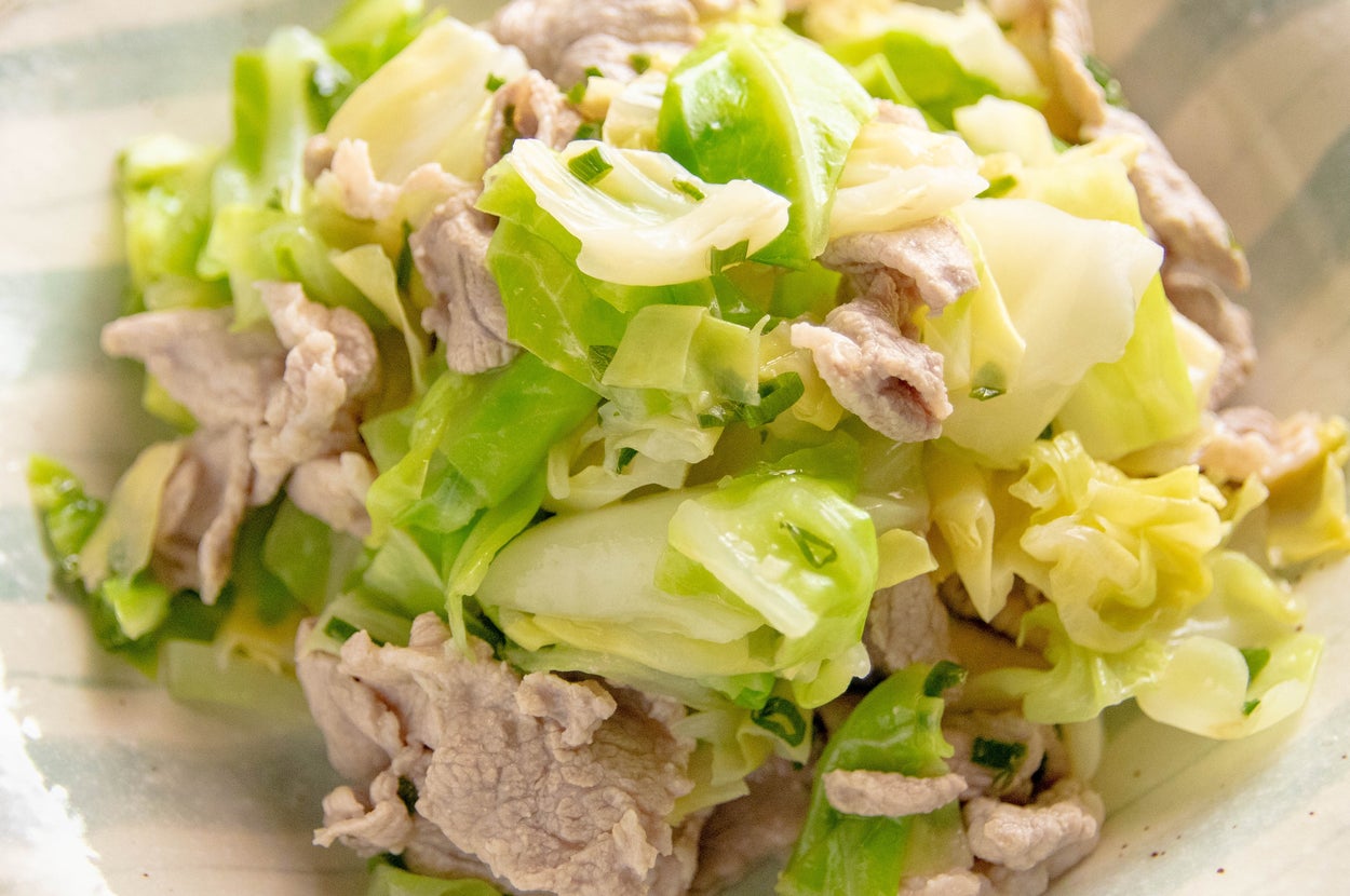 キャベツと豚肉のサラダが器に盛られている。料理は家庭的なシンプルさを感じさせる。