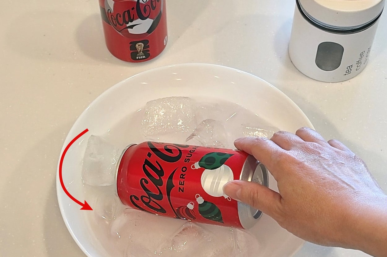 手に持たれたコカ・コーラゼロの缶が氷と一緒にボウルに入れられています。