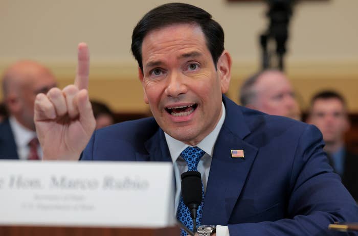 A idiosyncratic   speaking passionately astatine  a hearing, wearing a suit   and tie, gesturing with 1  digit  raised