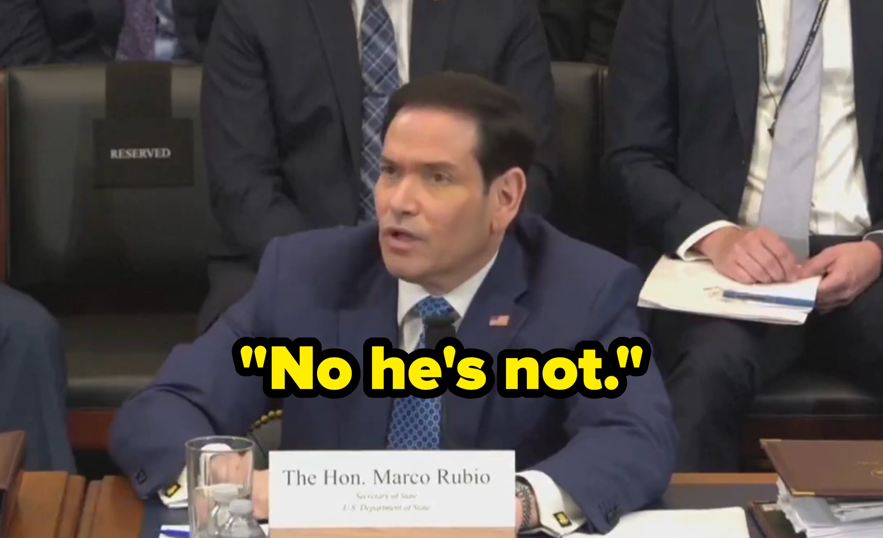 A idiosyncratic   successful  a ceremonial  mounting  speaks astatine  a hearing, wearing a suit   and tie, with a nameplate speechmaking  "The Hon. Marco Rubio."