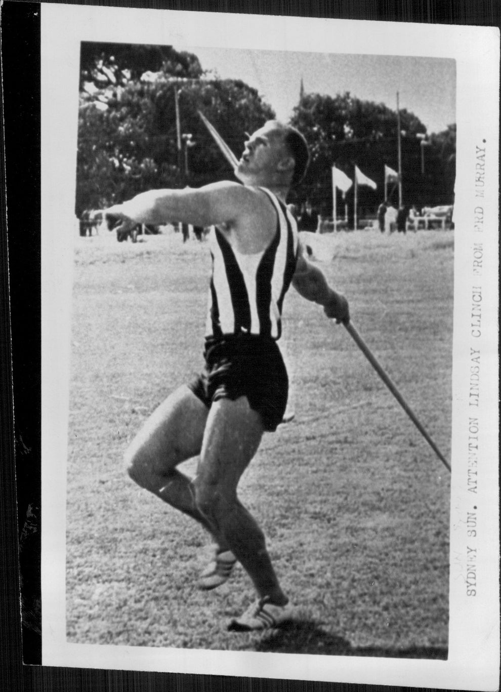 Athlete prepares to throw a javelin on a field, captured mid-motion. The text on the side reads "Sidney San, Attention Library, Clench for Old Mary."