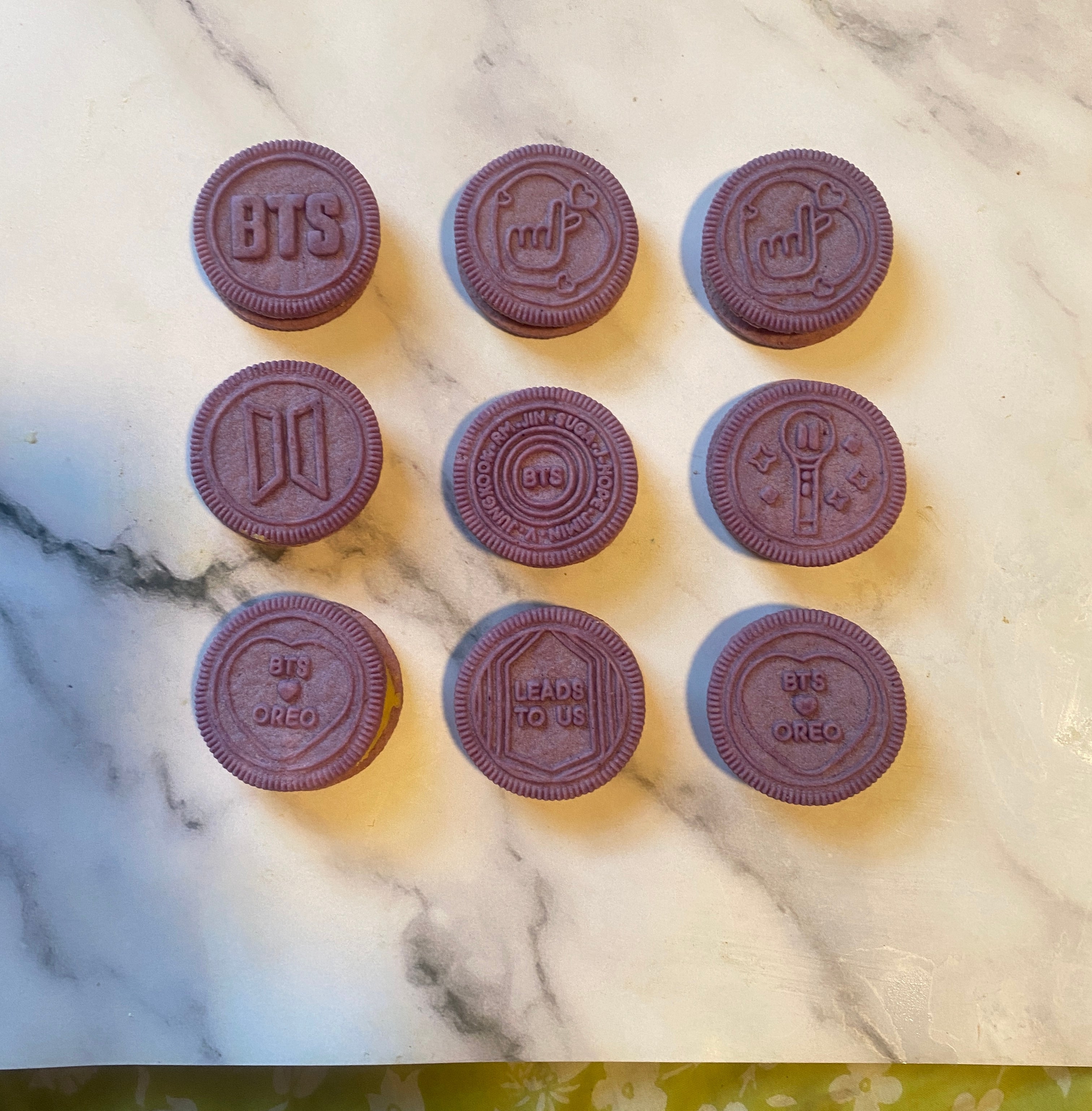Nine Oreo cookies with embossed BTS-related designs, including logos and text like "BTS" and "LEADS TO US."