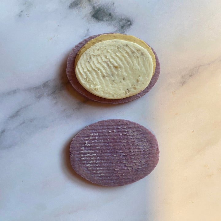 Two round wafers, one with cream filling, lie on a marble surface
