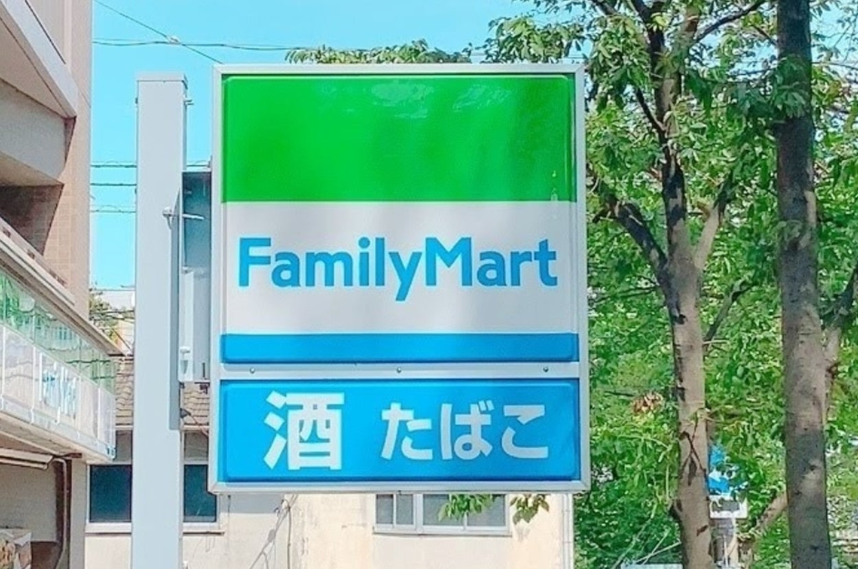 ファミリーマートの看板。下に「酒 たばこ」と表示。商店街の一角に位置。