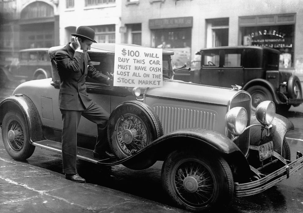 Man leans on vintage car with sign: "$100 will buy this car. Must have cash. Lost all on the stock market." It's a 1930s street scene