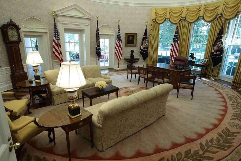 The Oval Office with classic furniture, flags, and a rug with a floral border