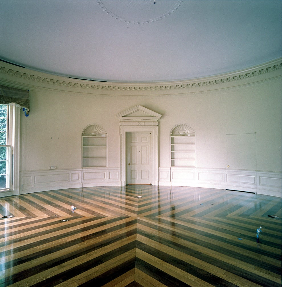 Empty room with ornate molding, two built-in shelves, and a polished wooden floor