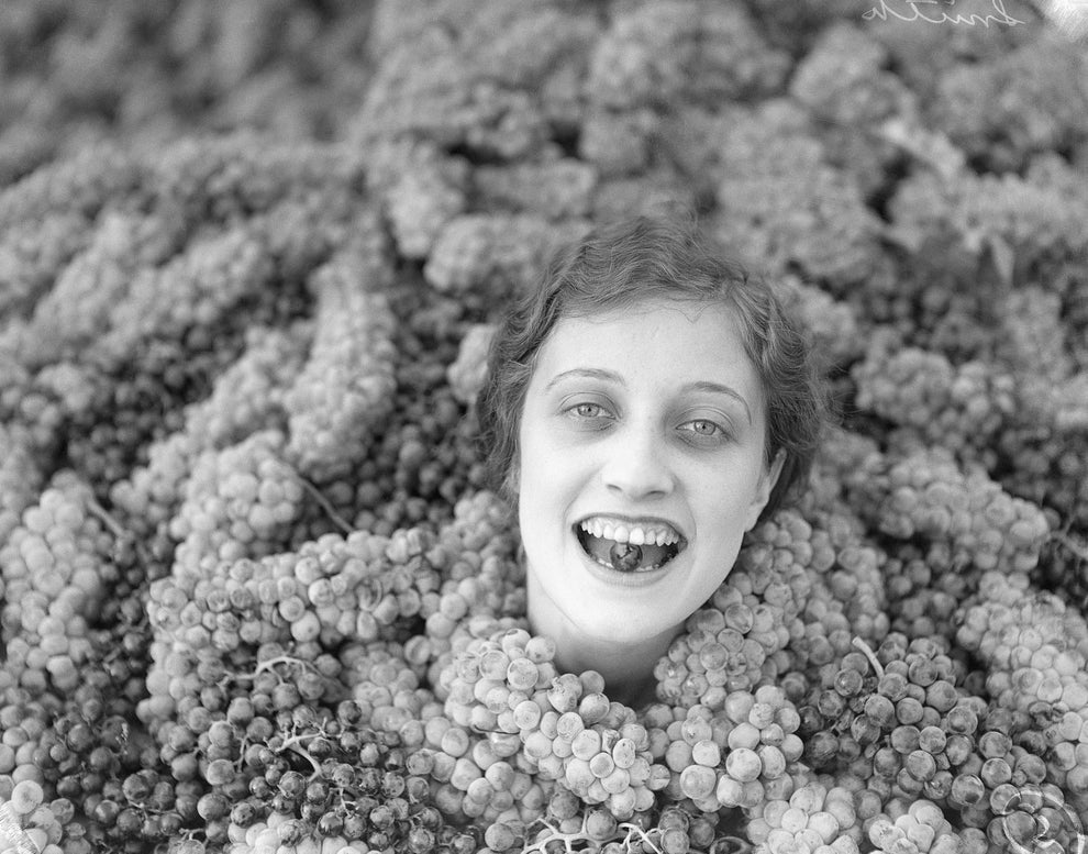 Person's head surrounded by grapes, smiling with grapes in their mouth, creating a playful and surreal image