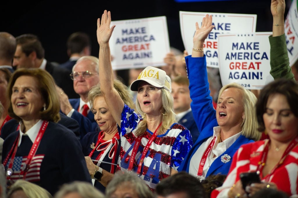 A assemblage  astatine  a governmental  rally holds "Make America Great Again" signs. A pistillate   successful  a star-patterned outfit raises her manus  enthusiastically