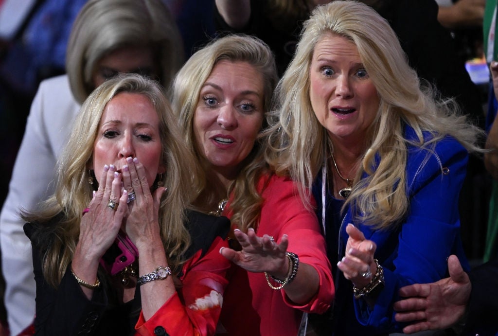 Three women successful  ceremonial  attire with amazed  expressions motion  toward thing  off-camera