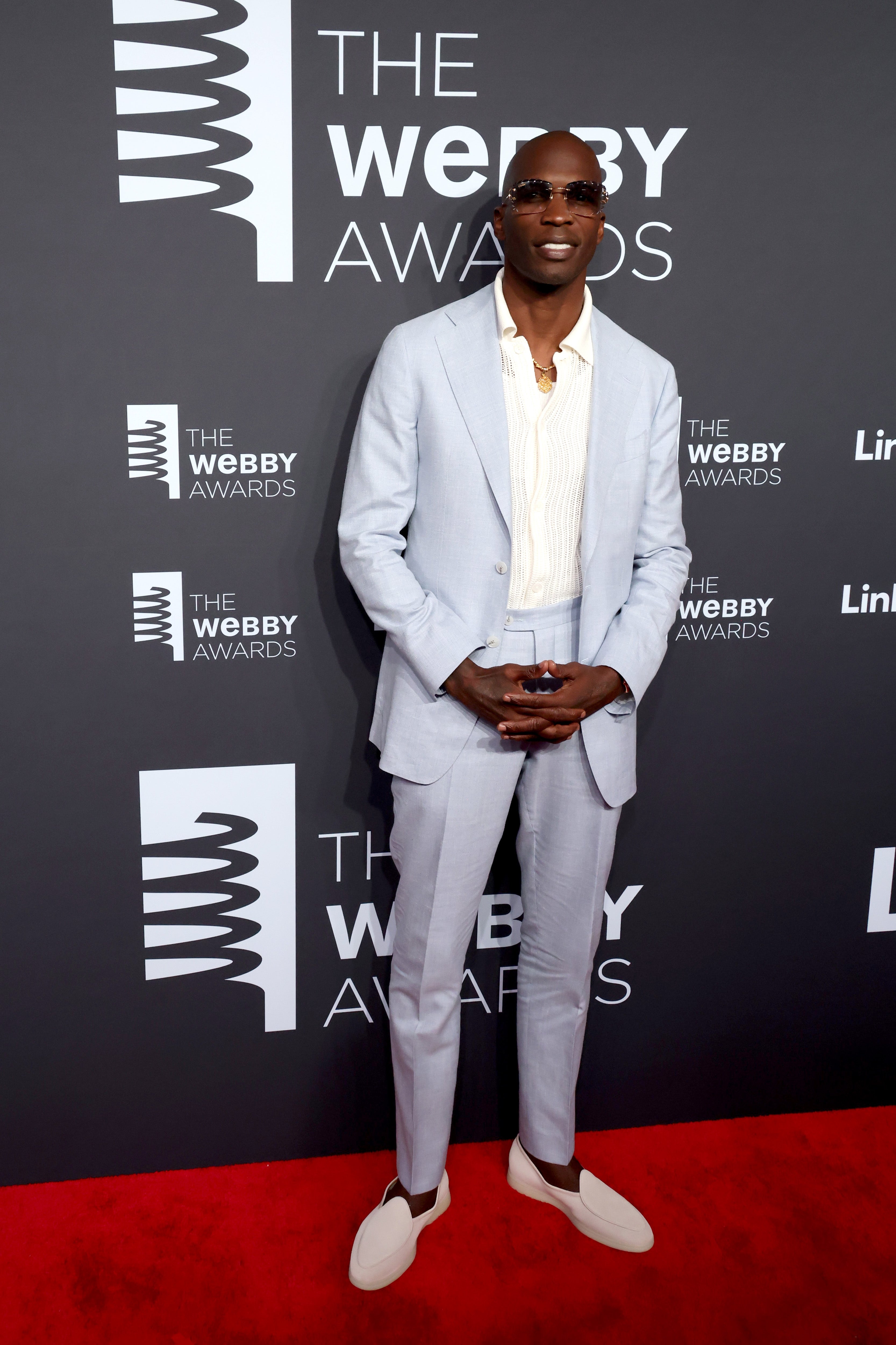 Person in a tailored suit and sunglasses on a red carpet at the Webby Awards
