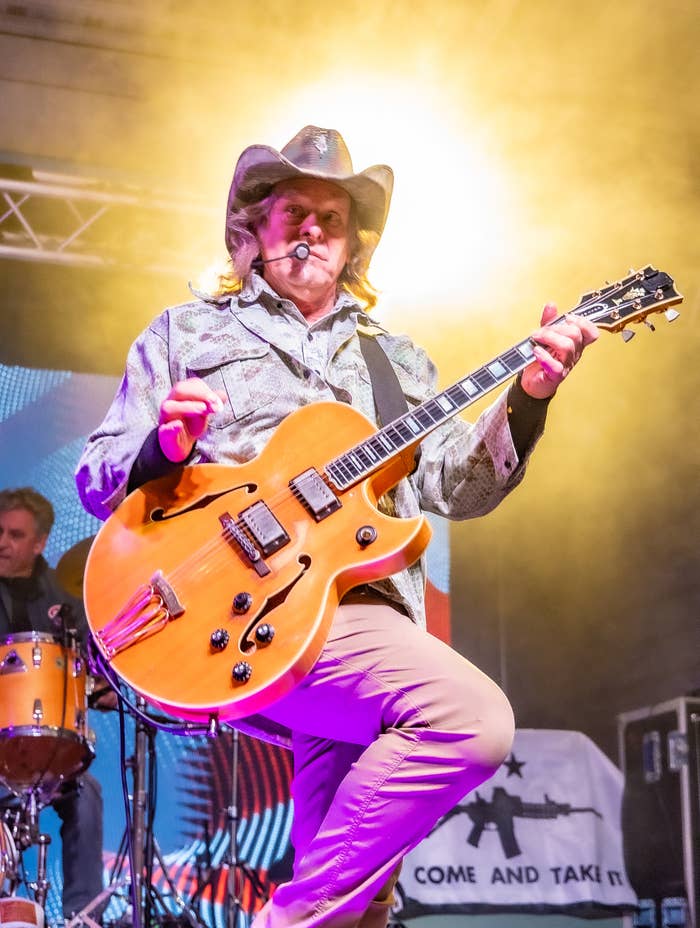Musician connected  signifier    wearing a cowboy chapeau  and patterned jacket, playing a guitar energetically during a unrecorded  performance