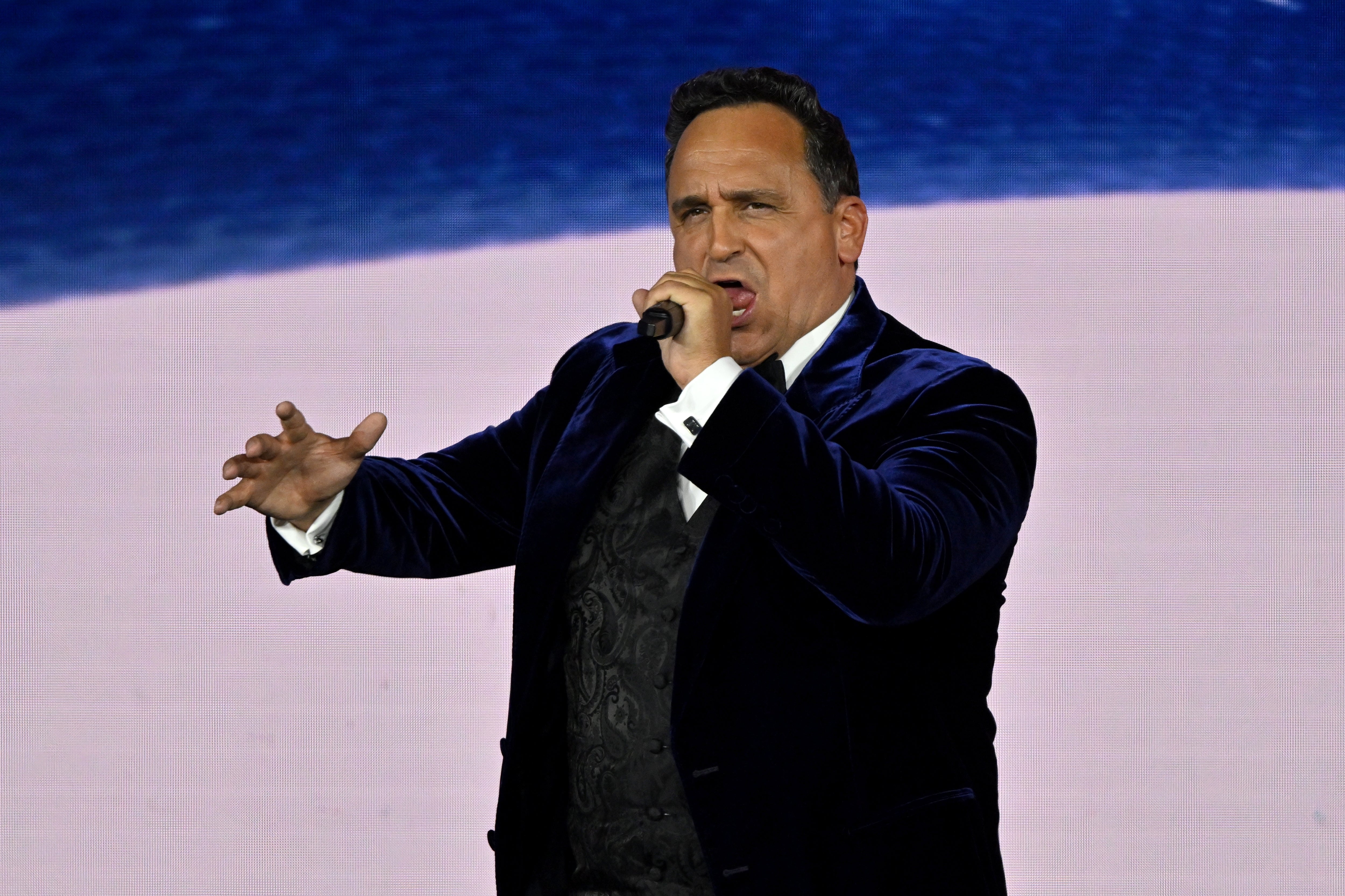 Person successful  a velvet suit   passionately sings connected  stage, holding a microphone, with dynamic manus  gestures