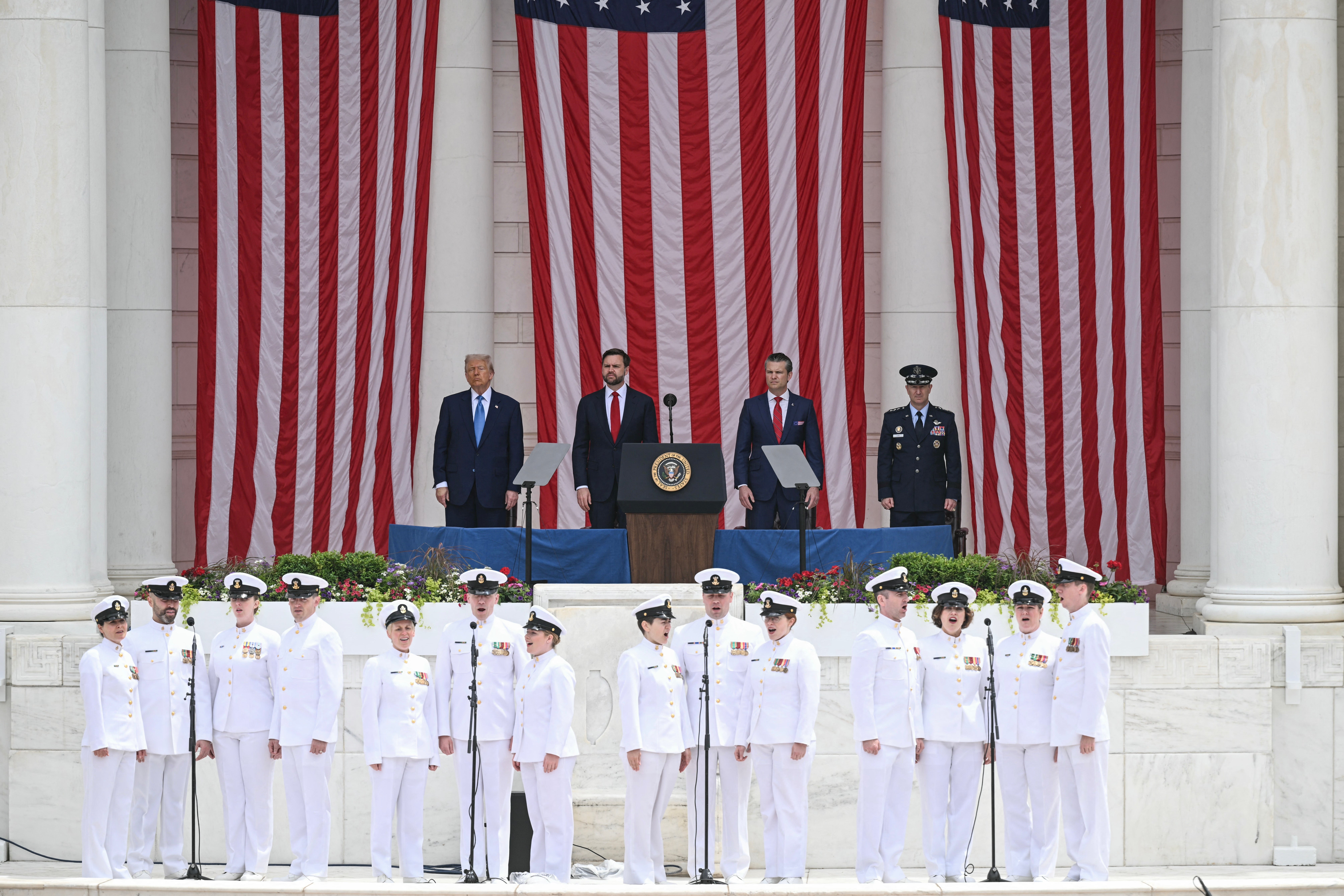 A choir successful  naval uniforms sings successful  beforehand   of a signifier    with officials and ample  American flags successful  the background