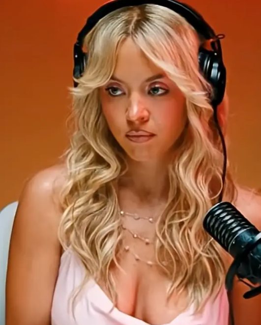 Person with long, wavy hairsbreadth  wearing headphones and a delicate necklace, speaking into a microphone