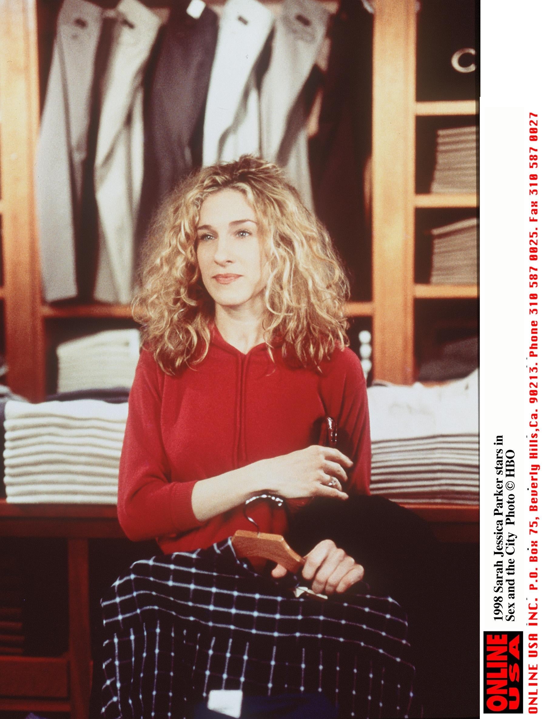Person sitting connected  a stack of folded apparel  successful  a store, holding a hanger, wearing a casual outfit with a long-sleeve apical  and plaid pants