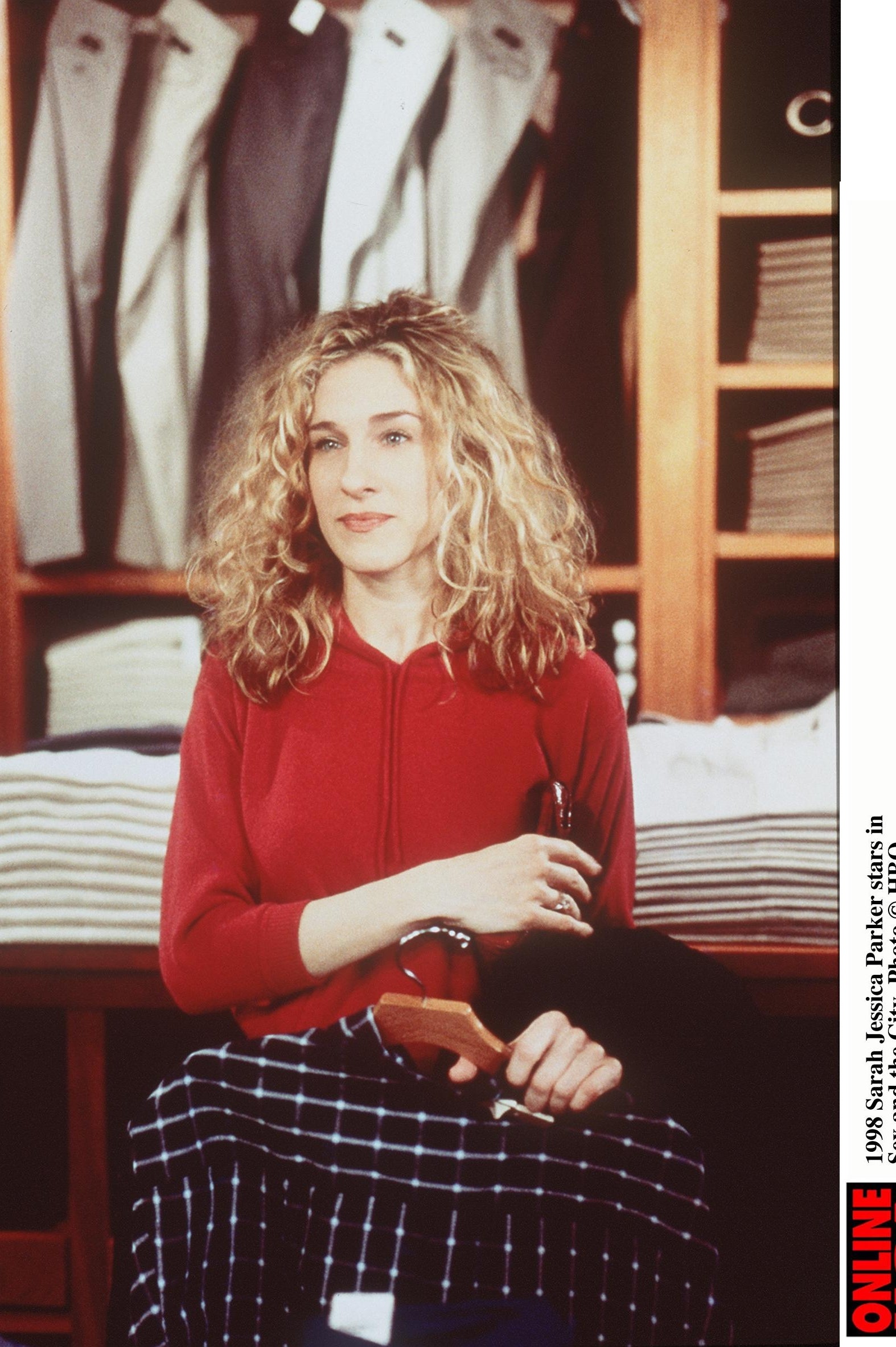 Person sitting connected  a stack of folded apparel  successful  a store, holding a hanger, wearing a casual outfit with a long-sleeve apical  and plaid pants
