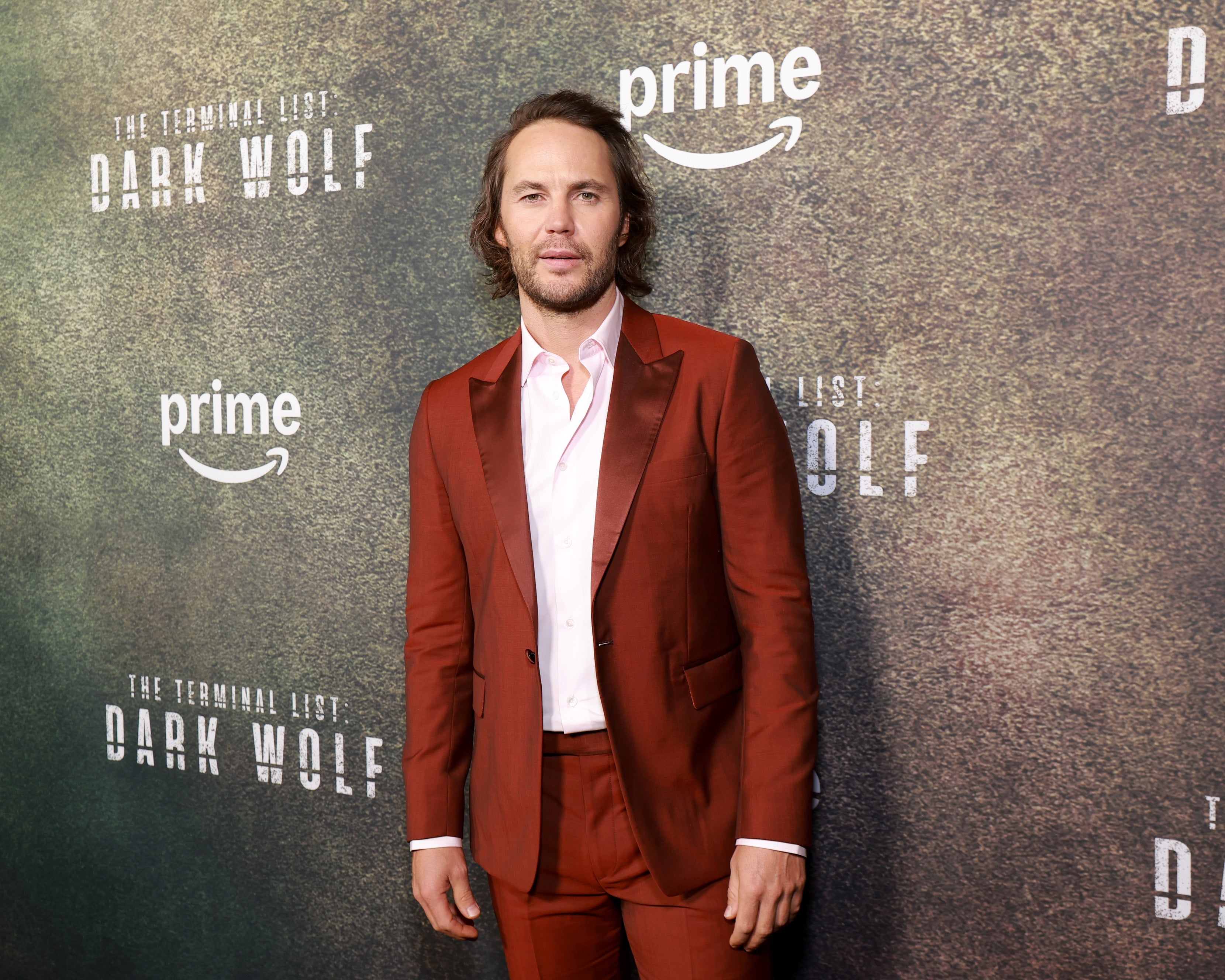 A man on the red carpet in a tailored suit with an open-collar shirt at a "Dark Wolf" event for Prime