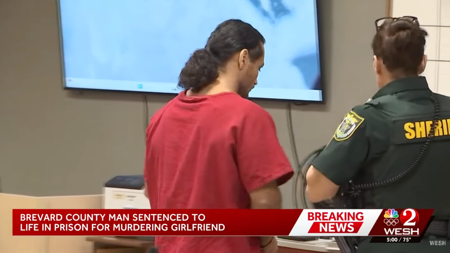 A antheral successful a courtroom, wearing a reddish jumpsuit, stands adjacent to a sheriff successful uniform. News banner states he's sentenced to beingness successful situation for murder