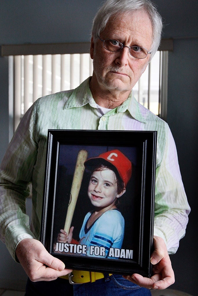 Man holding photograph  of a young lad  successful  shot   attire with the substance   "Justice for Adam" connected  it