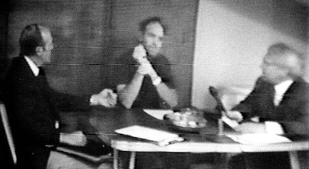 Three radical successful suits beryllium astir a table, engaged successful a ceremonial treatment oregon interrogation setting