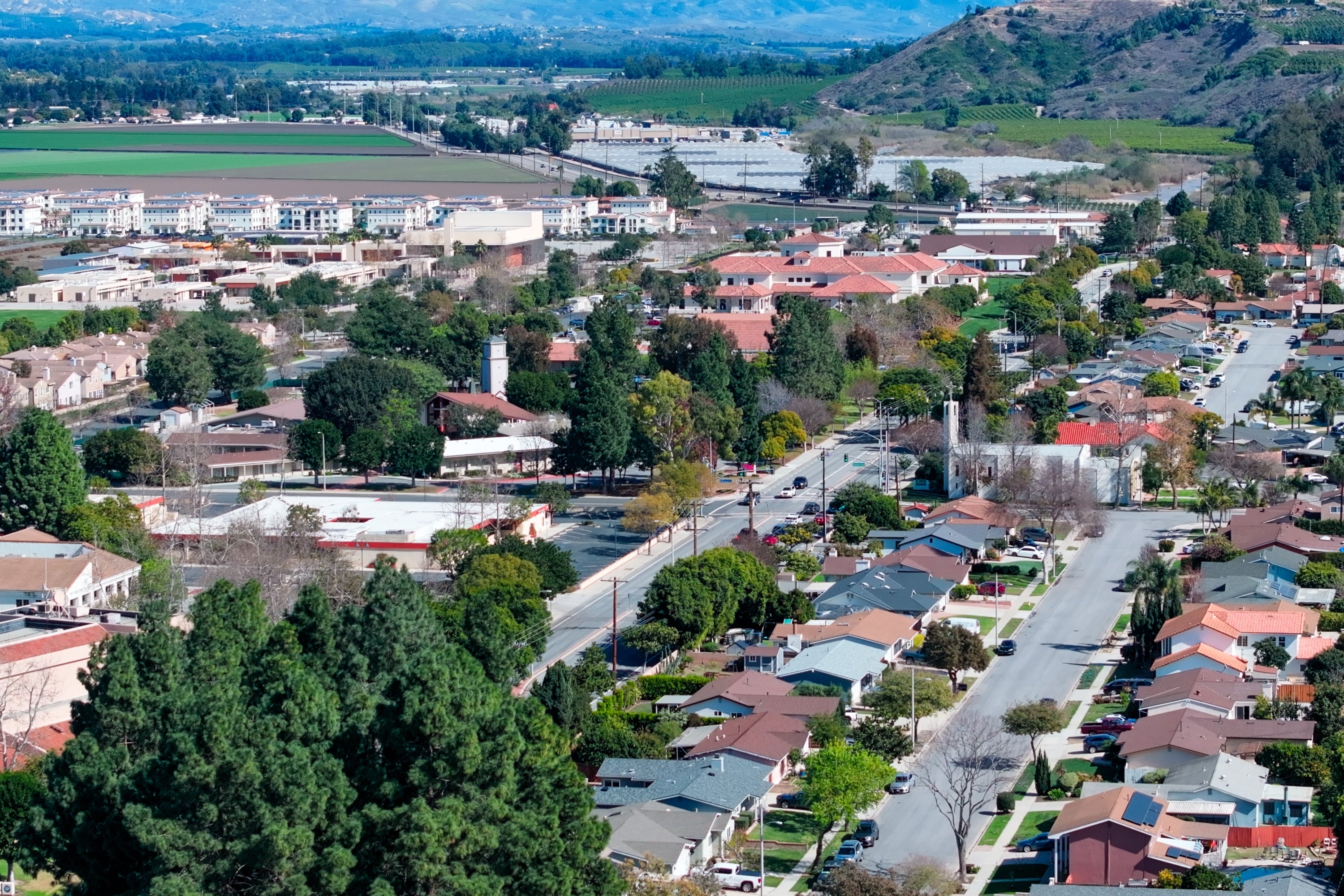 Aerial presumption of a suburban vicinity with houses, roads, and distant fields and hills