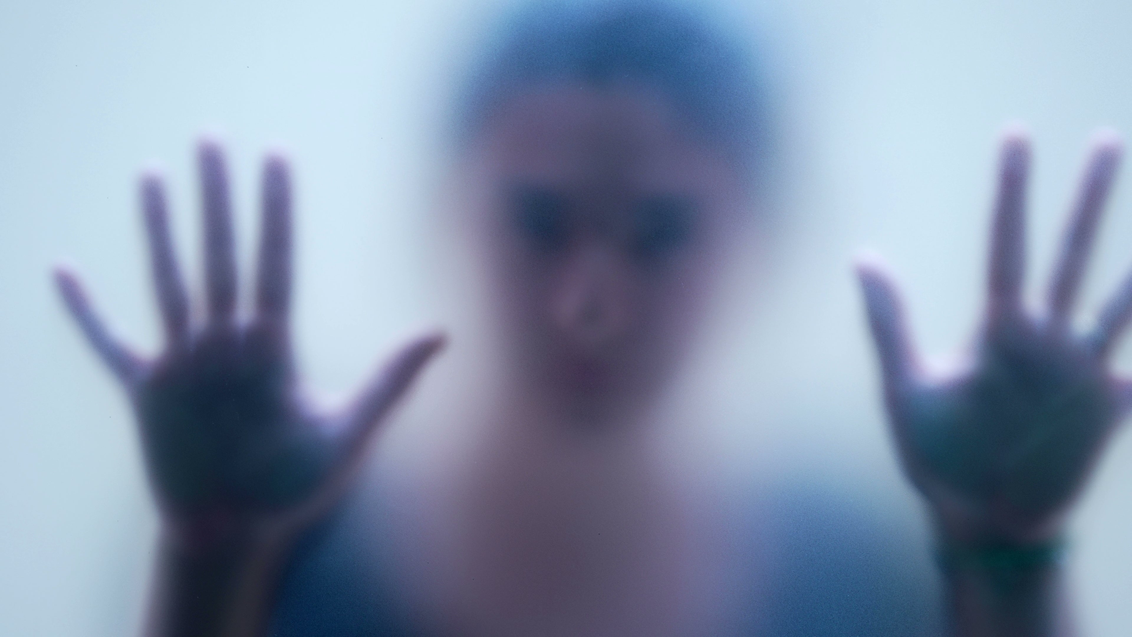 A idiosyncratic with blurred features presses their hands against a foggy solid surface, creating a consciousness of enigma and emotion