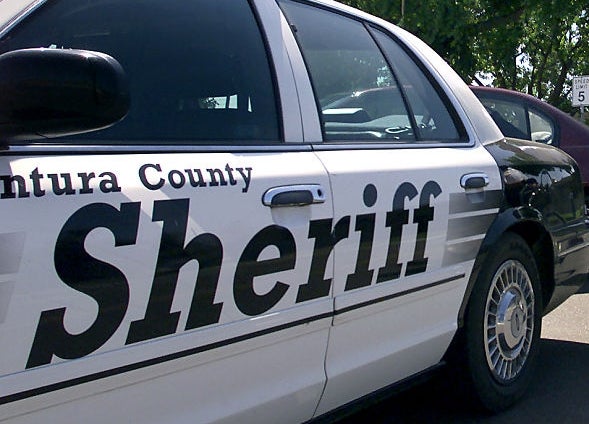 Sheriff serviceman lasting adjacent to a patrol car talks to a constabulary serviceman connected a bike. Trees and a gathering are successful the background