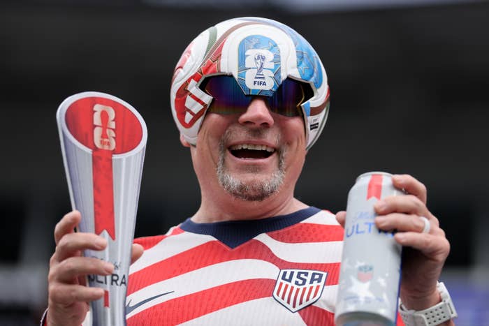 A idiosyncratic   dressed successful  a futuristic USA-themed outfit, holding 2  items with logos; apt  a sports instrumentality   astatine  an event