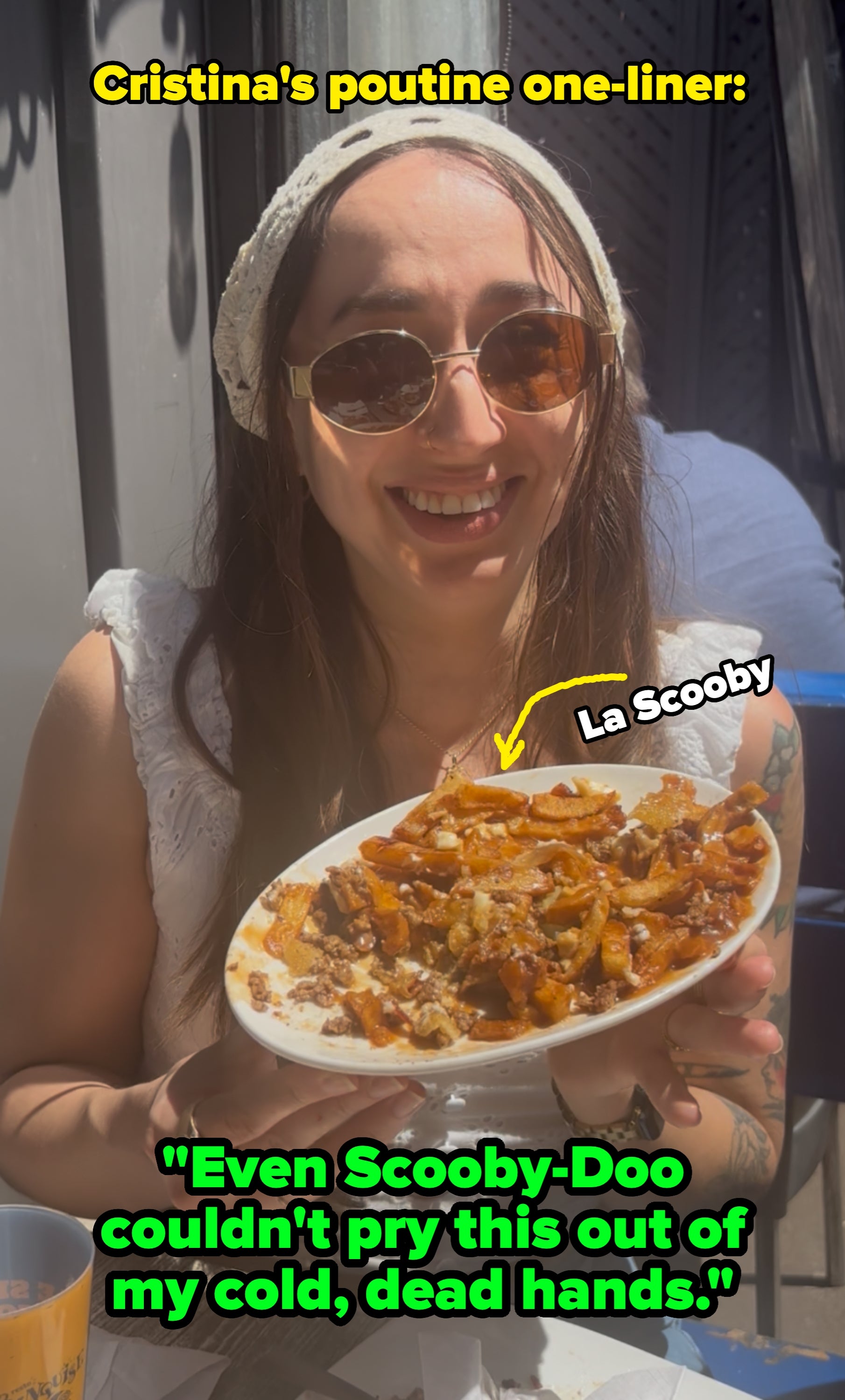 Person with abbreviated hairsbreadth sitting outdoors, holding a sheet of food, smiling gladly astatine it. People are seated astatine tables successful the background