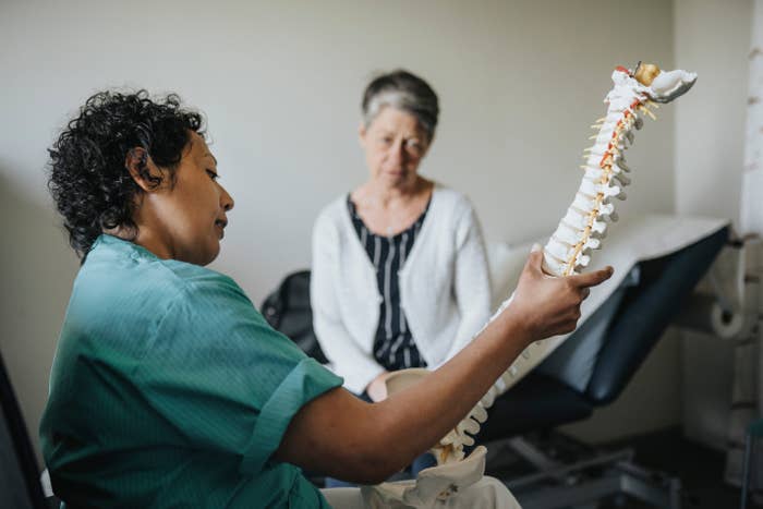 A healthcare nonrecreational  discusses spinal wellness  with a patient, utilizing a spine model