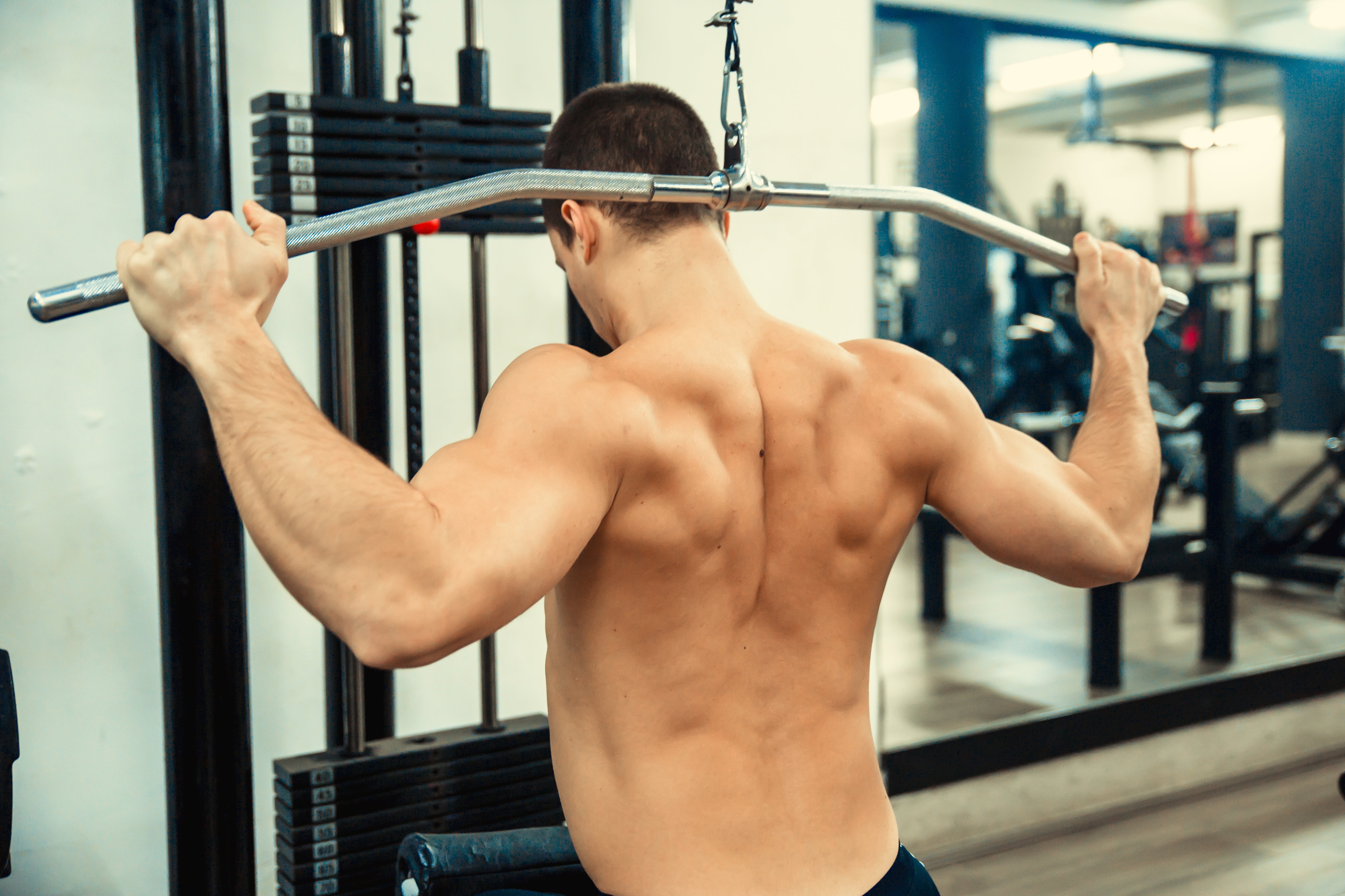 Man doing a lat pulldown workout successful a gym, focusing connected his backmost muscles
