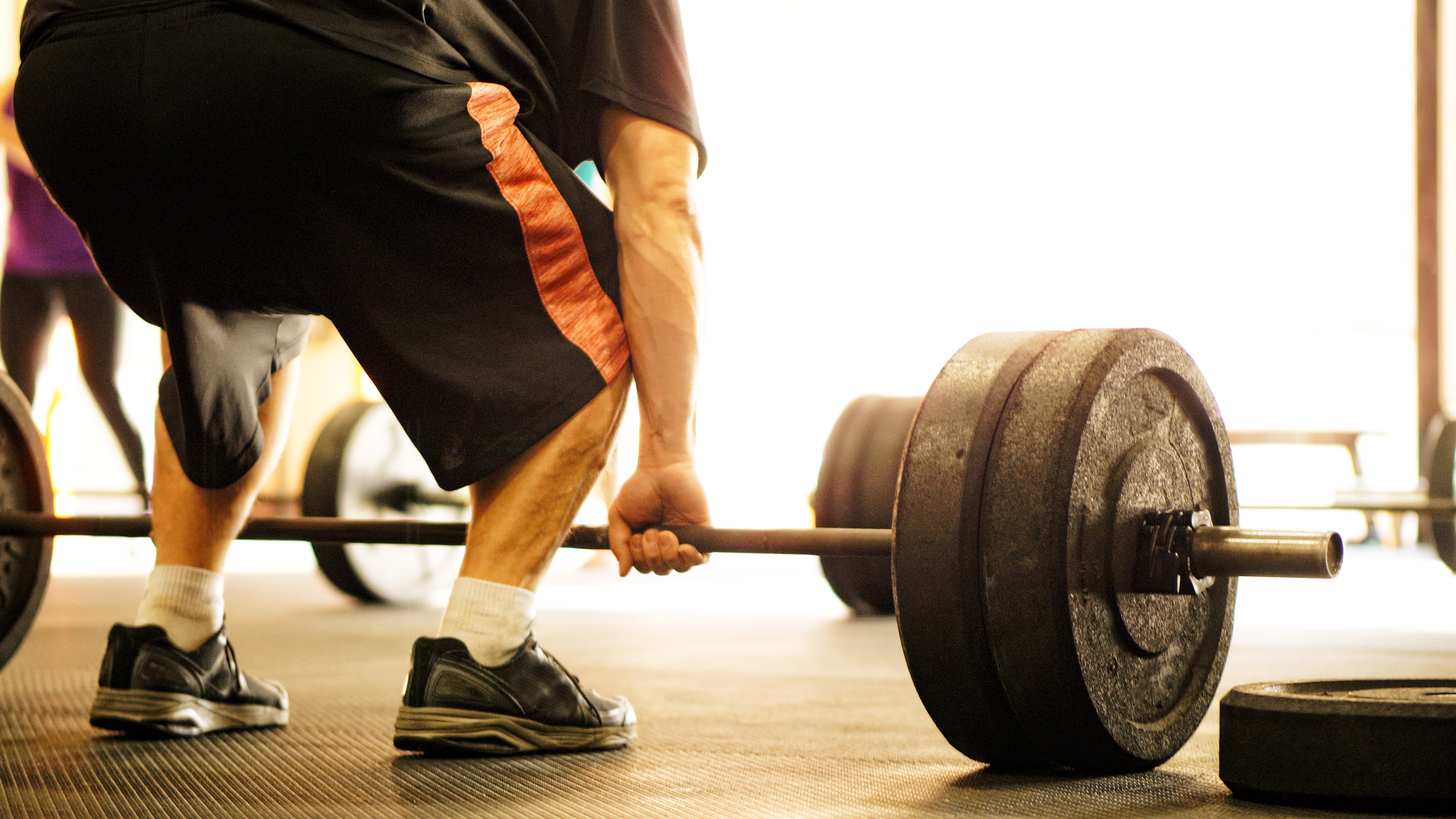 Person lifting a barbell with dense weights successful a gym, focusing connected spot grooming and fitness