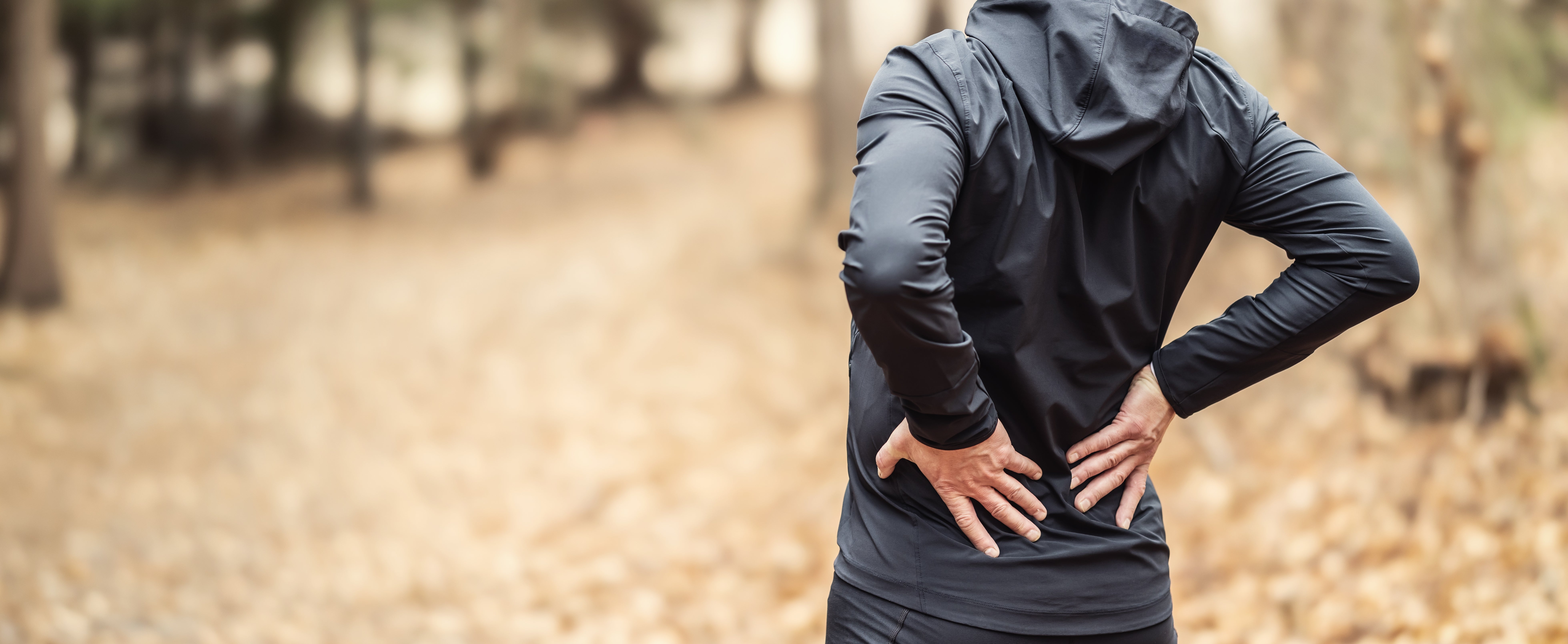 Person successful diversion covering holding their little backmost outdoors, surrounded by fallen leaves, suggesting backmost symptom oregon discomfort