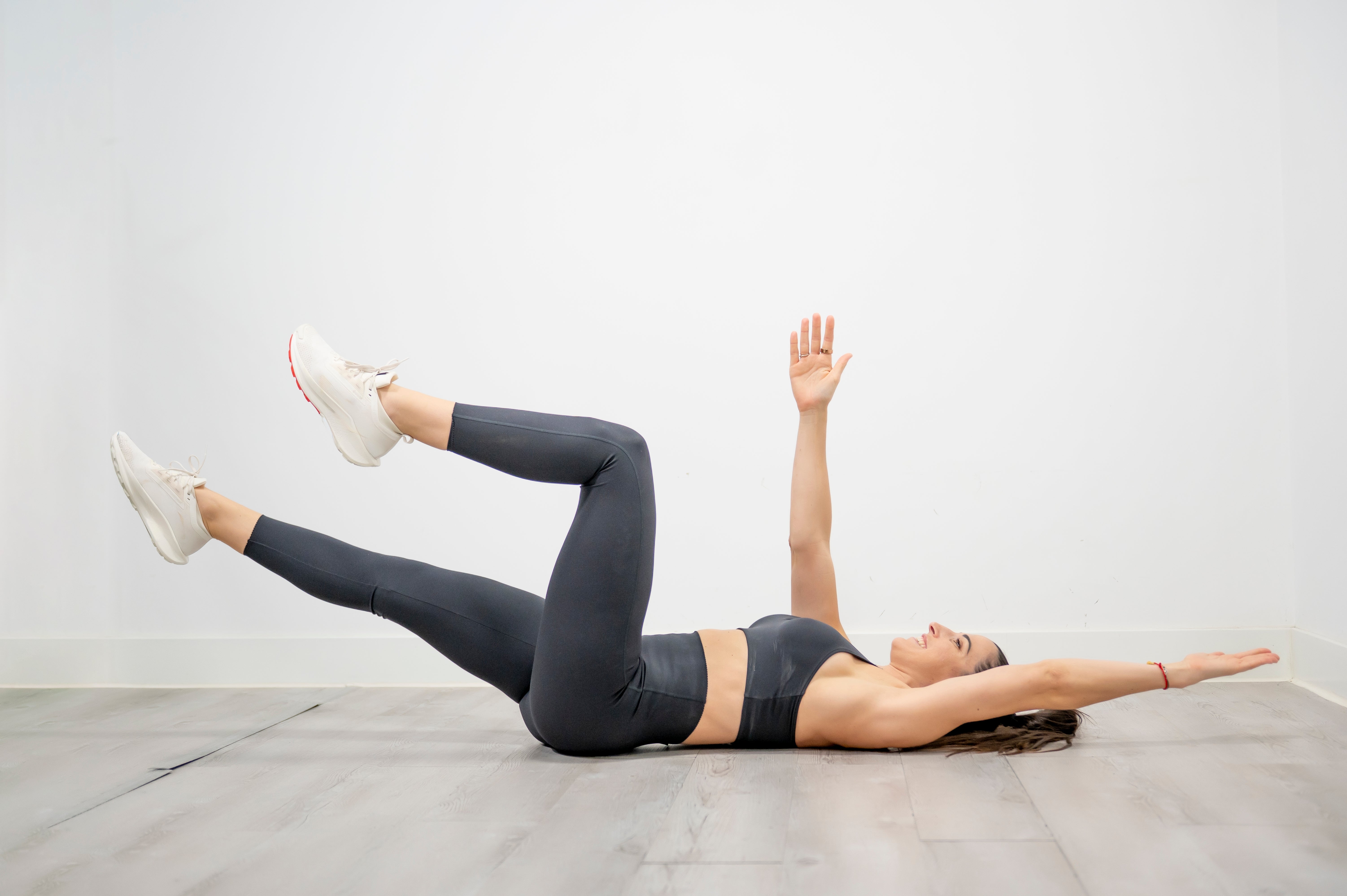 A idiosyncratic performs a dormant bug workout connected the floor, lying connected their backmost with arms and legs extended, demonstrating a halfway workout move