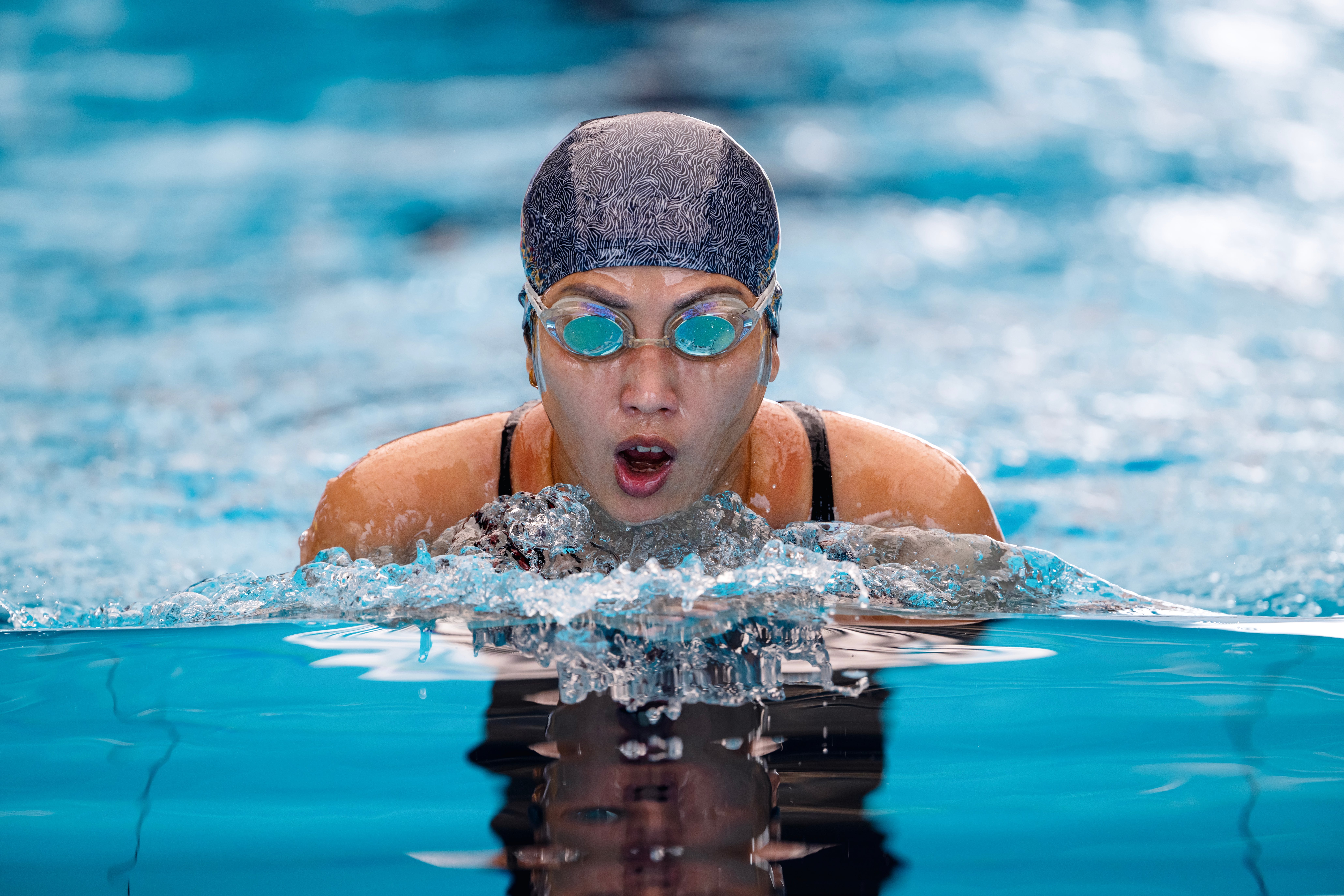 Swimmer successful goggles and aquatics headdress doing the breaststroke successful a pool, focused and determined