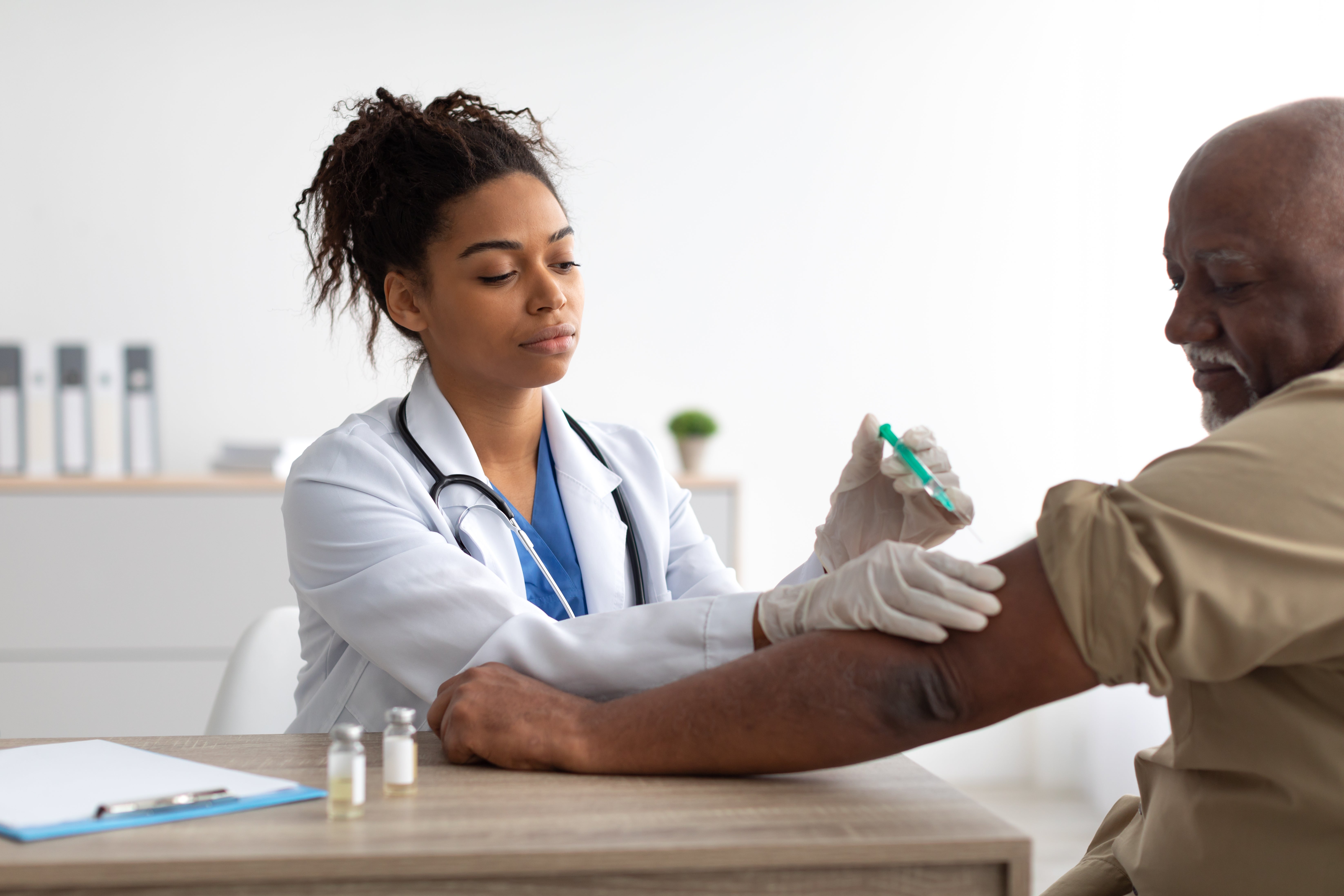 A doc  administers a vaccine to an aged  diligent  successful  a aesculapian  office, some  focused connected  the procedure