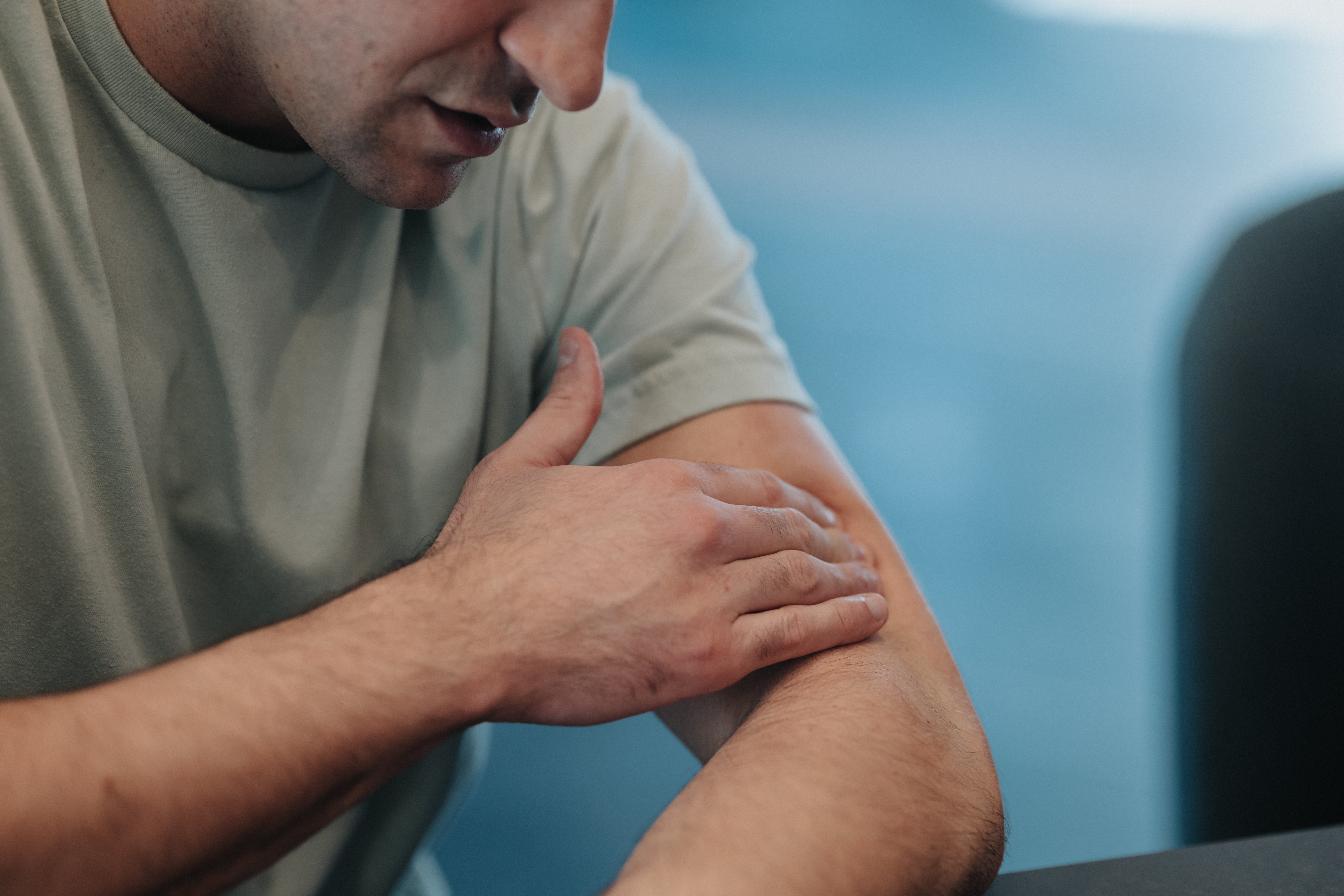 Person touching their arm, appearing thoughtful oregon  introspective
