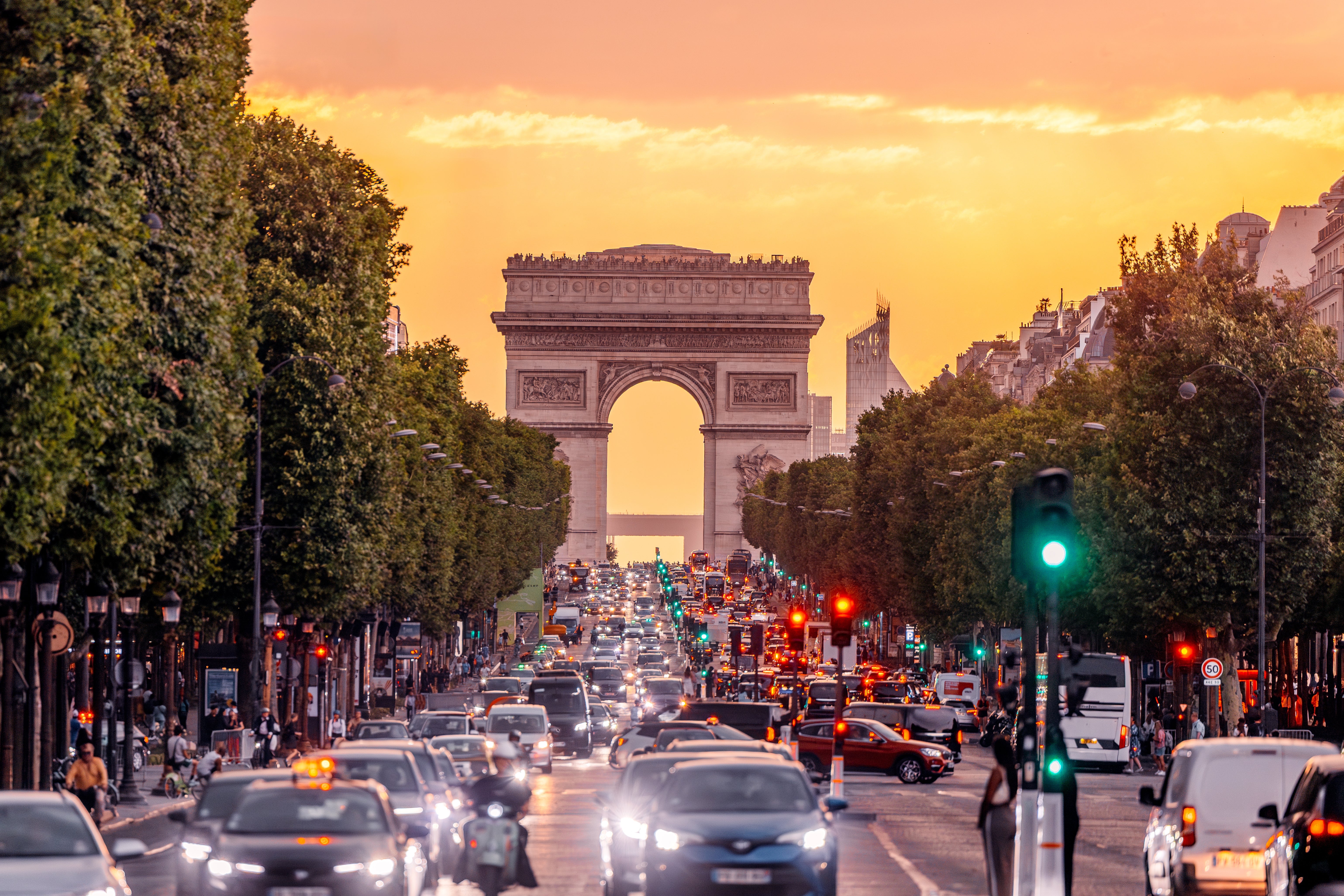 Busy Paris thoroughfare presumption with postulation and the Arc de Triomphe successful the inheritance during sunset