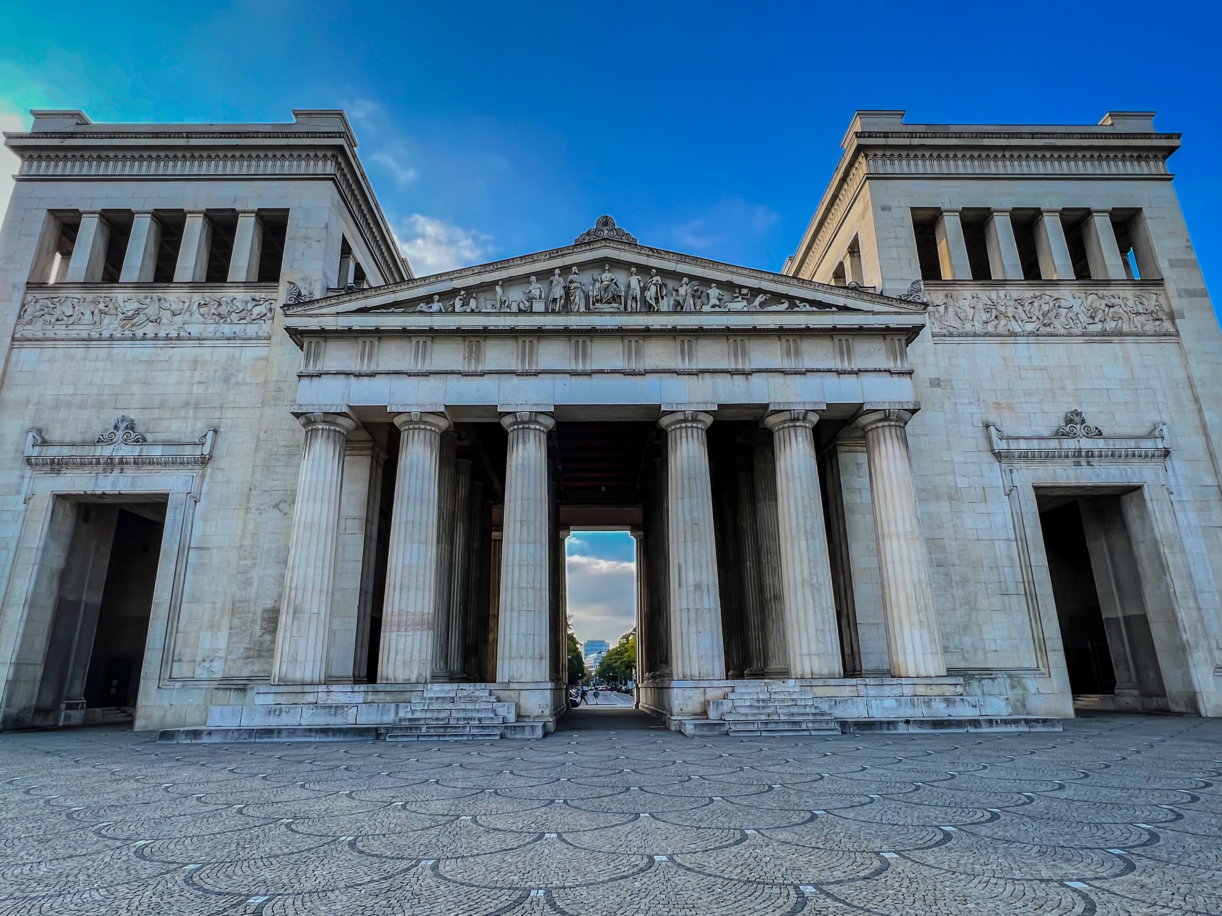 Neoclassical gathering with ample columns and ornate carvings, resembling past Greek architecture