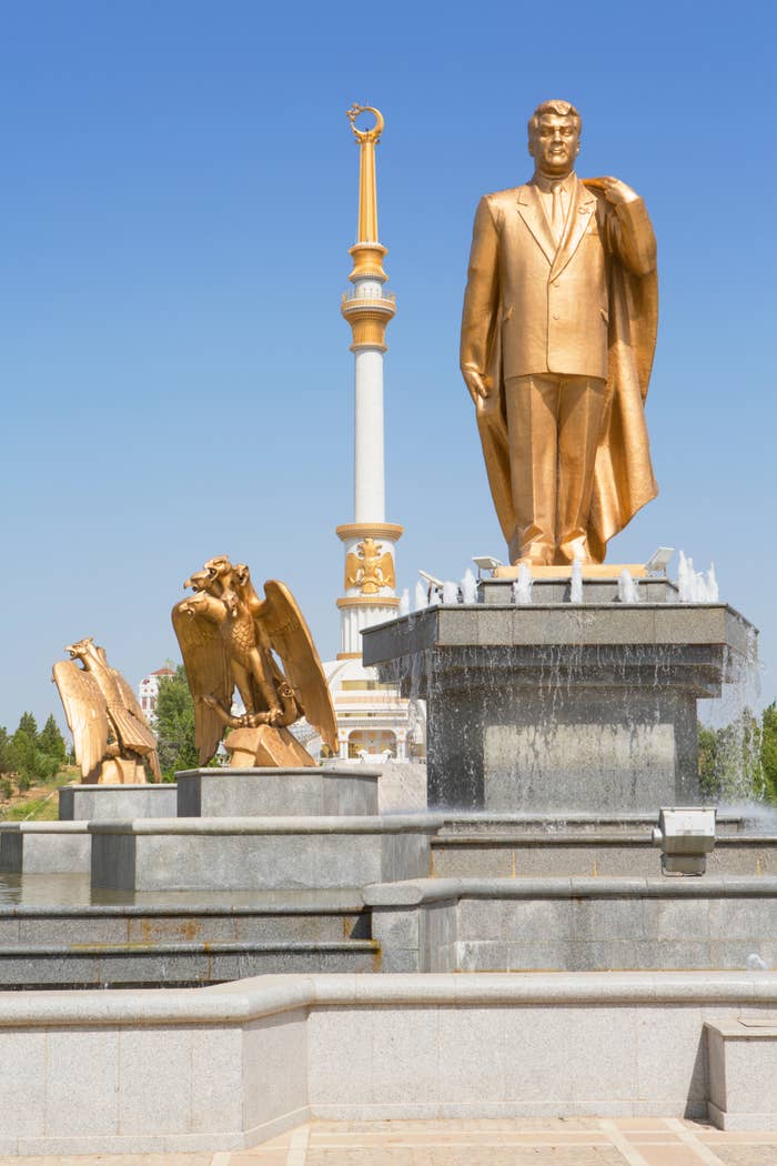 Golden statue of a antheral   successful  a suit   with a cape stands atop a fountain, accompanied by eagle sculptures. A gangly  file  with an emblem is successful  the background