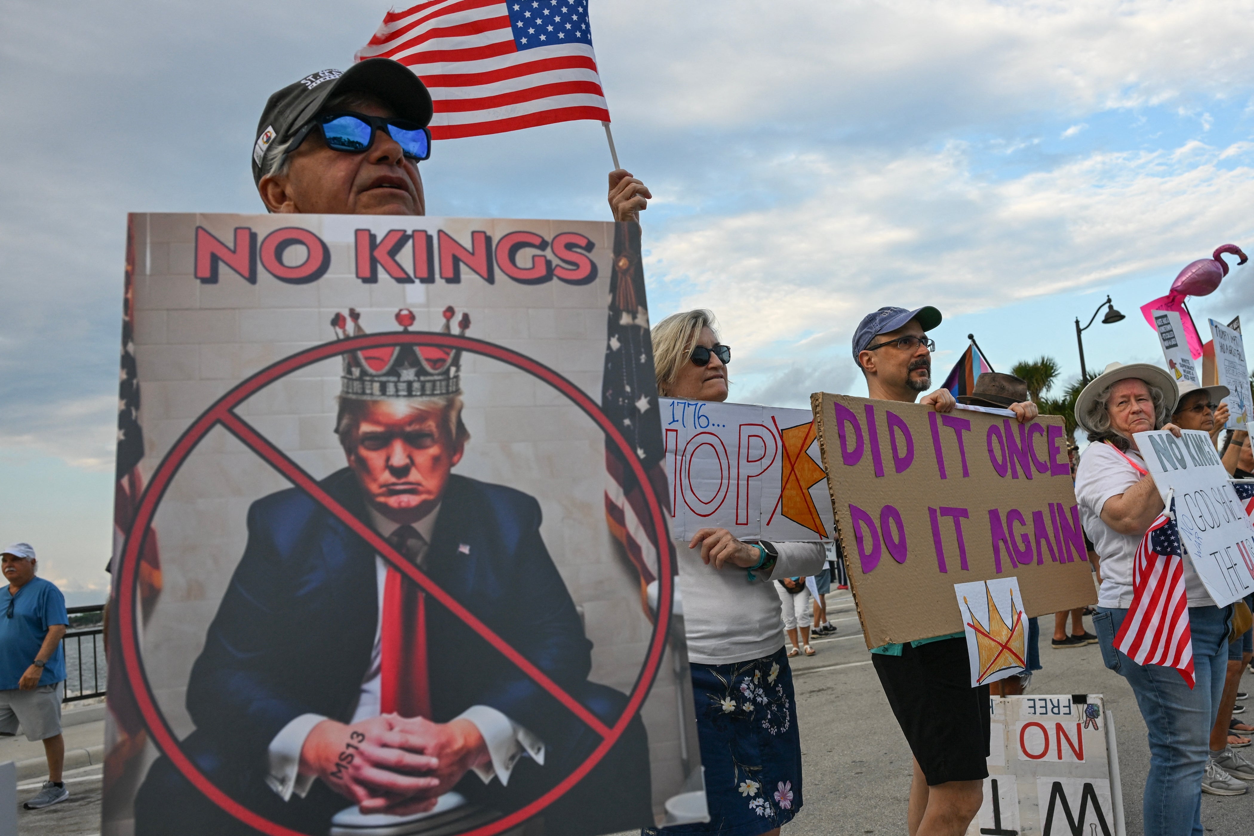 People astatine a protestation clasp anti-Trump signs, including 1 depicting Trump arsenic a king. American flags are displayed