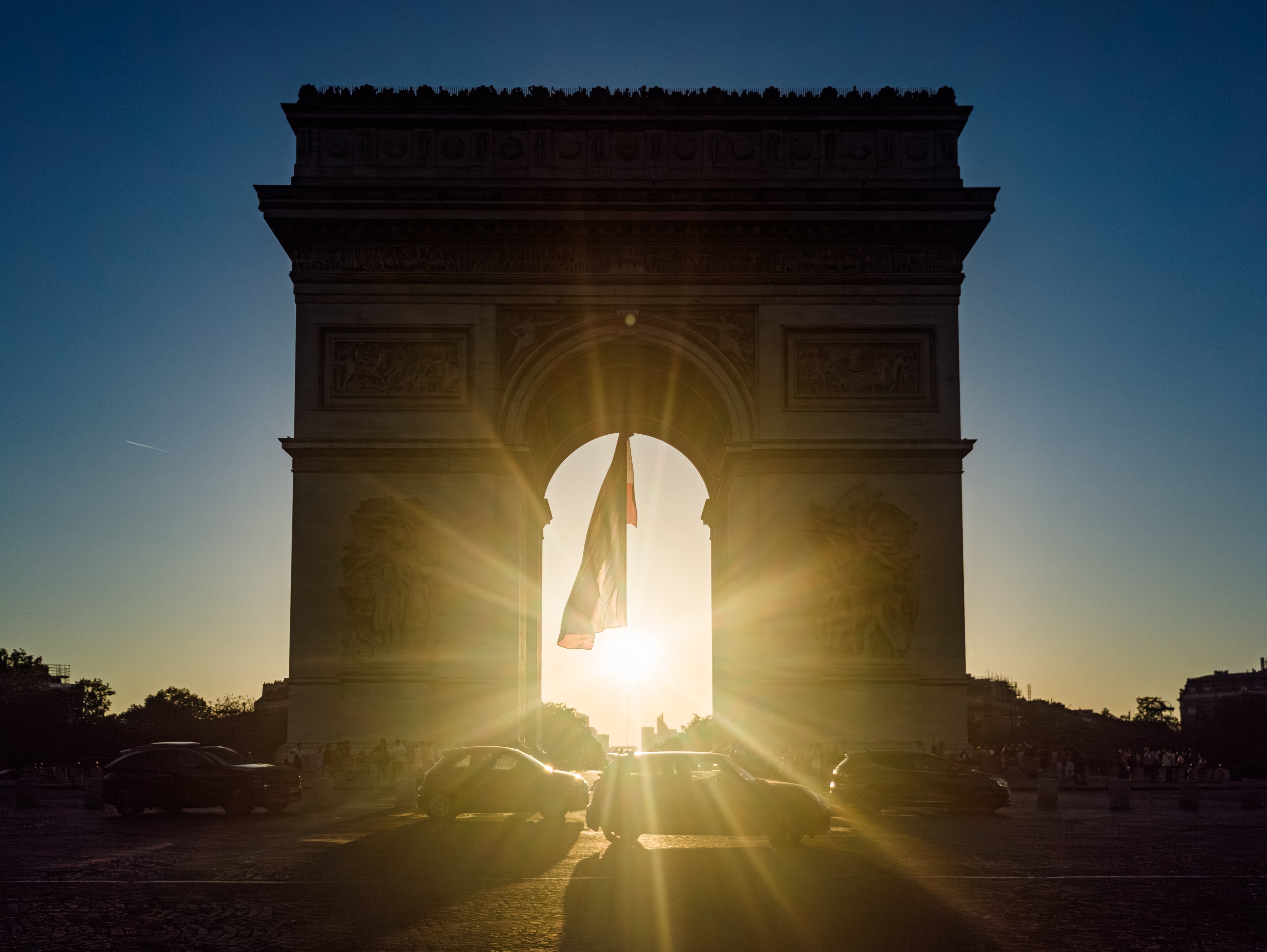 The Arc de Triomphe successful silhouette with a agleam prima glowing done its archway; a fewer cars walk by